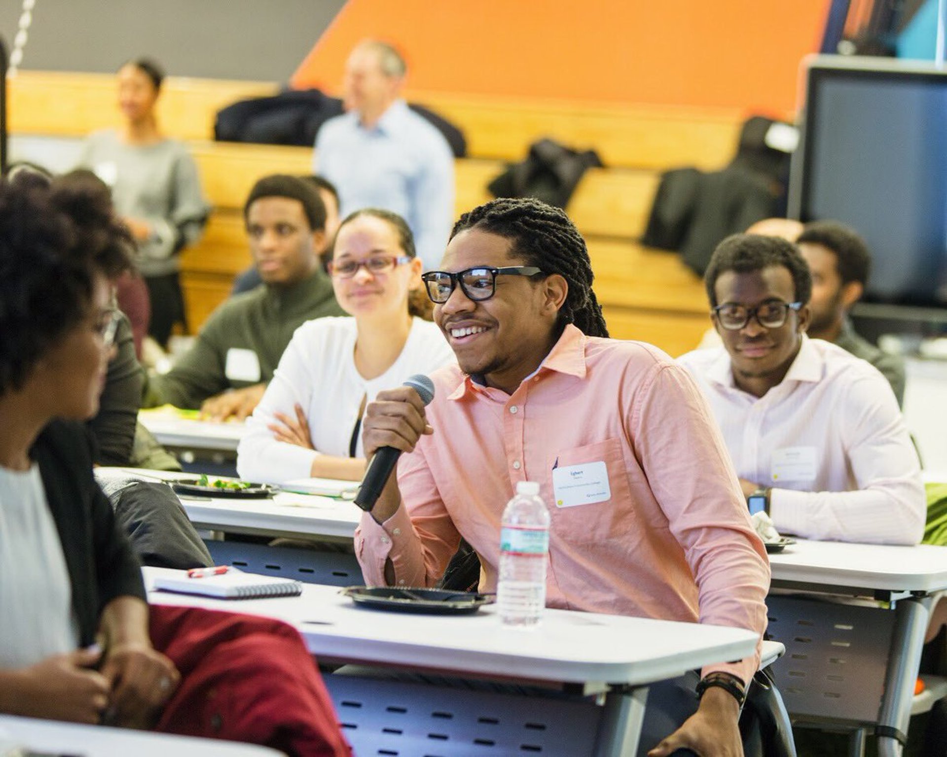 grayscale photo of man in suit jacket writing on paper