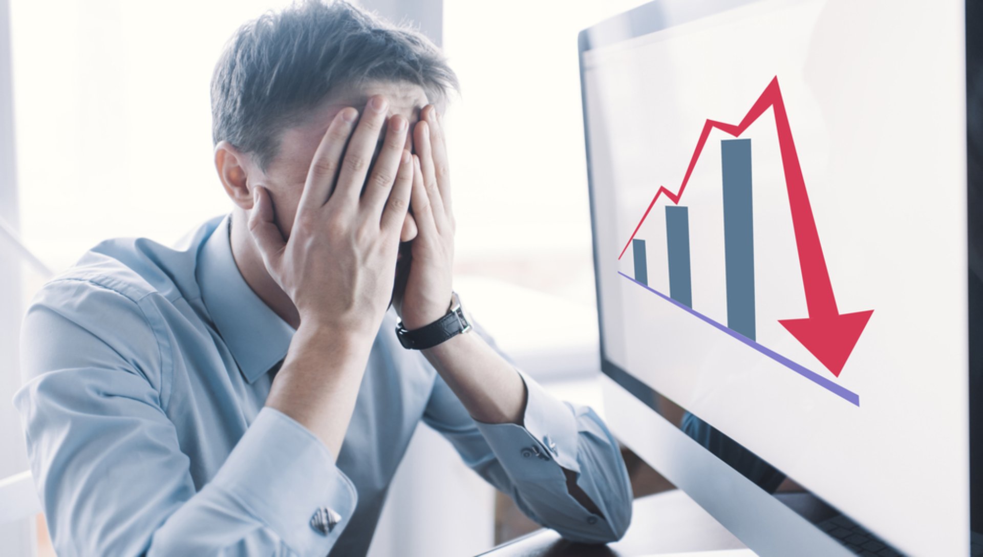 Man rubbing his face in front of laptop.