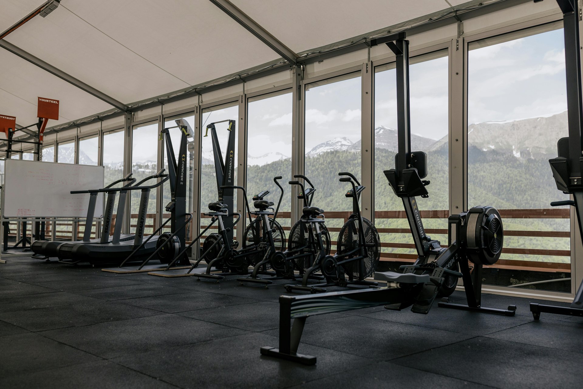 A row of treadmills in a gym with windows