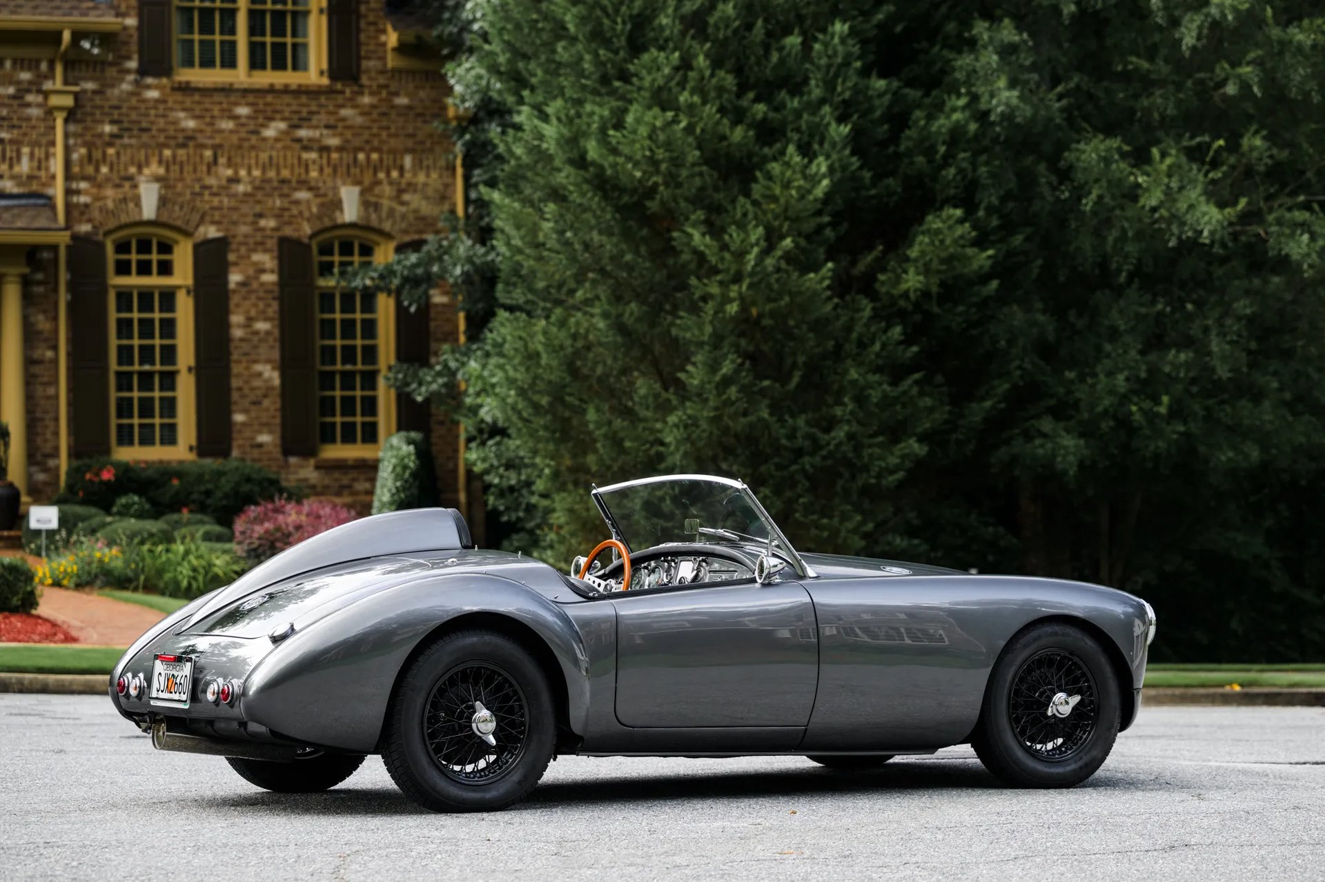 A side profile shot of a silver and black 1958 MG MGA Roadster in an elegant English courtyard