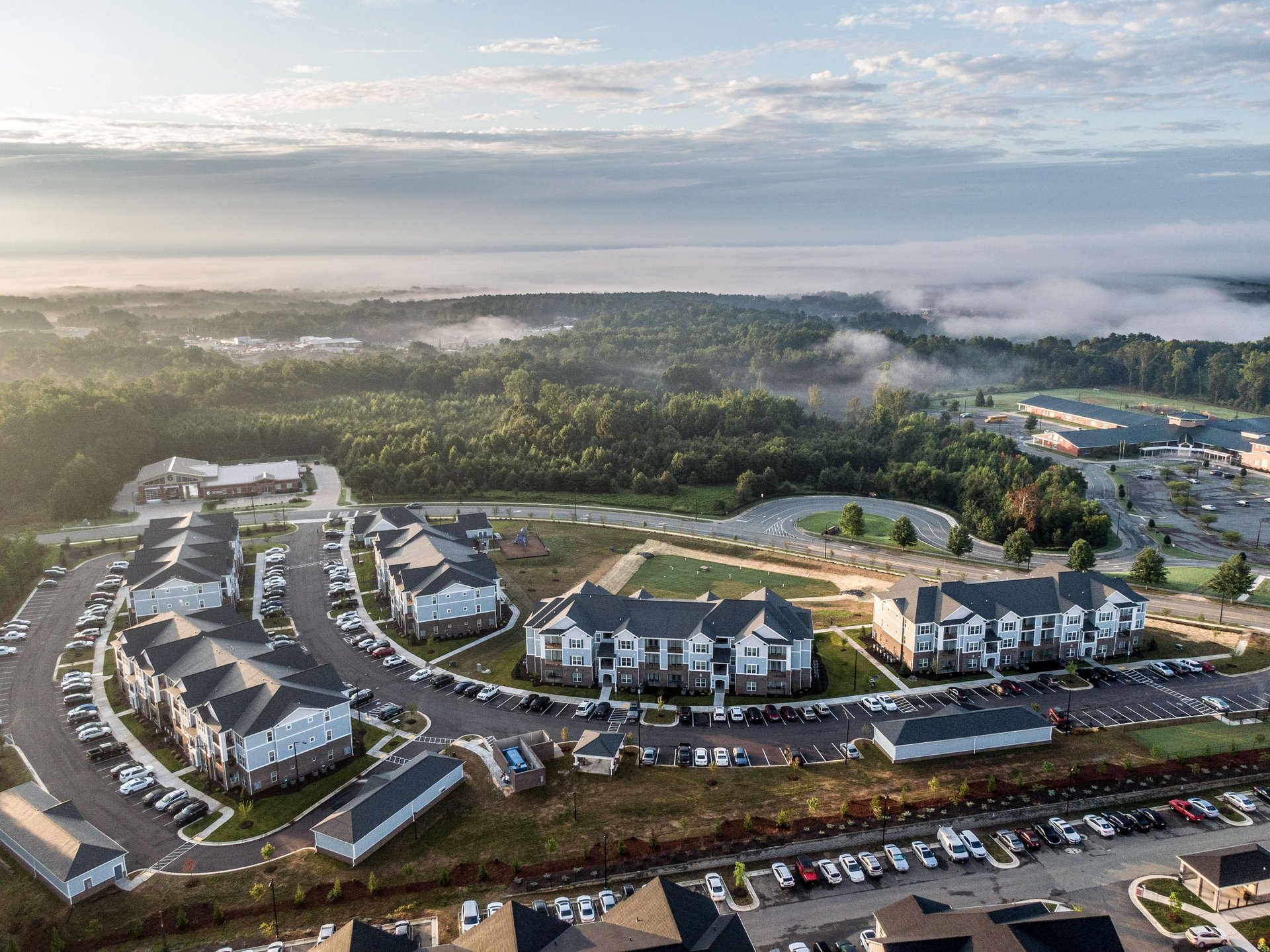 Aerial view of a completed multifamily apartment community with residential buildings, parking areas, and green space.