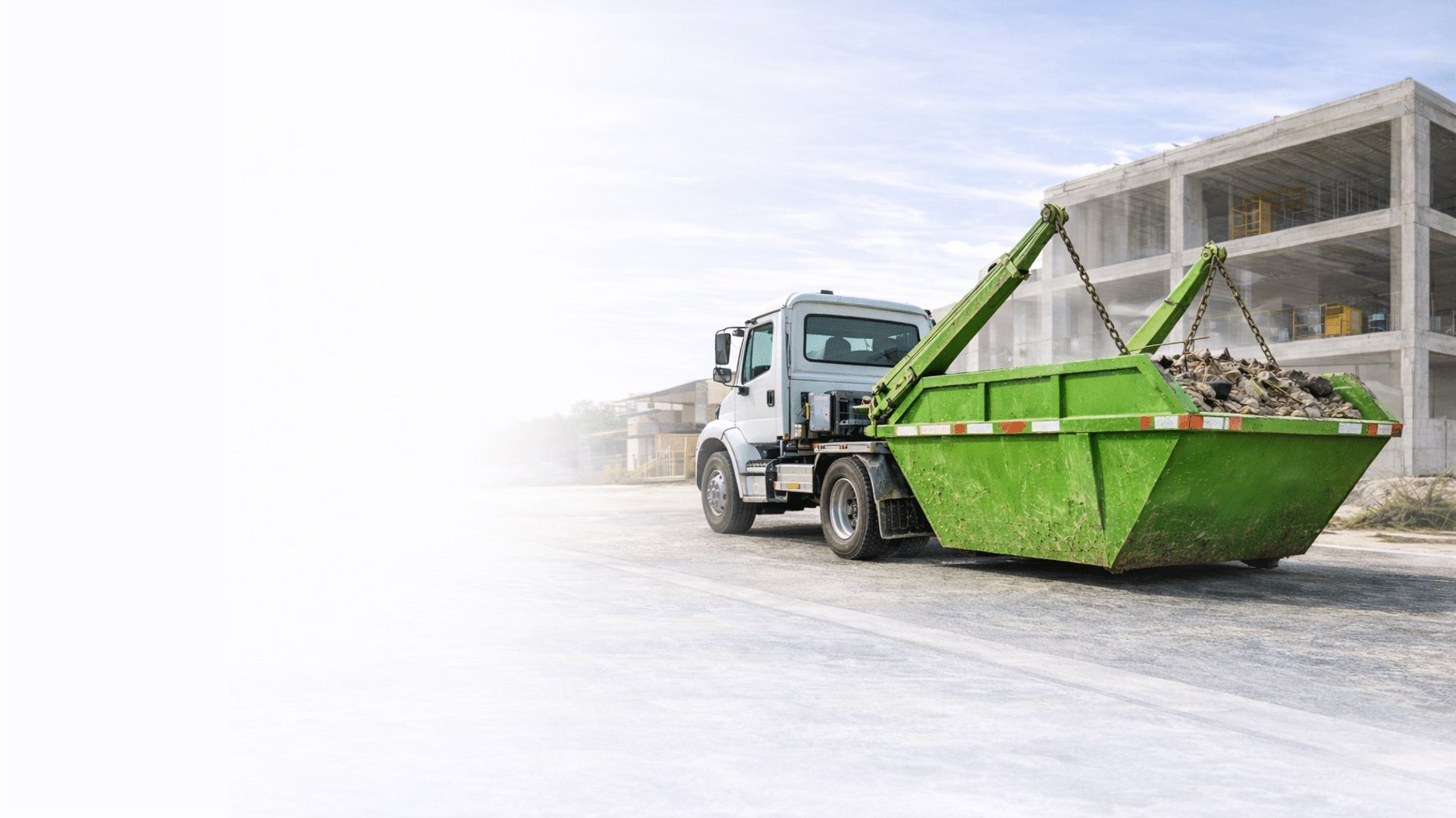 Caminhão caçamba basculante de cor brancar, levantando a caçamba de entulho verde em um construção