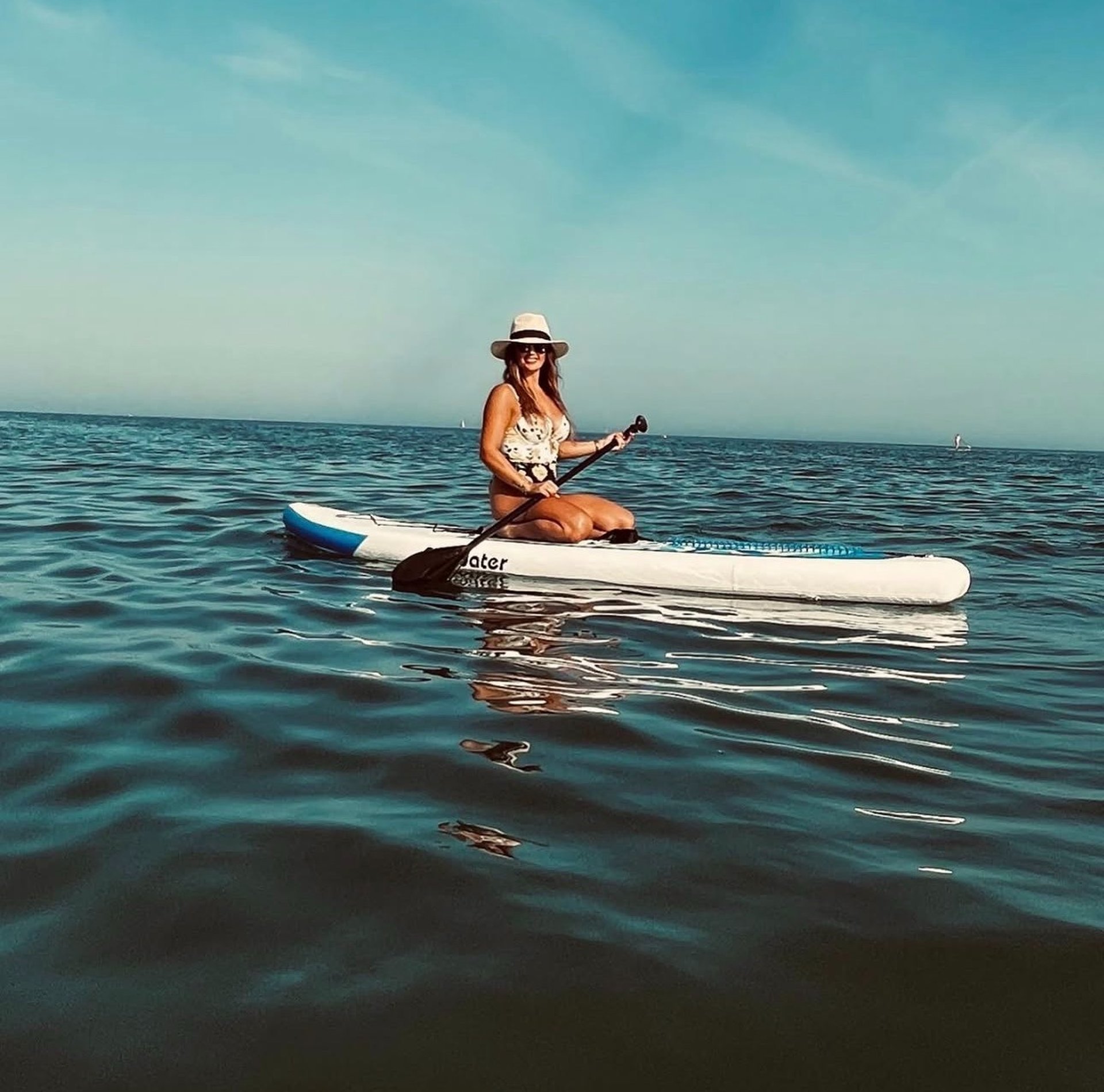 a woman in a bikini paddling a kayak in the ocean