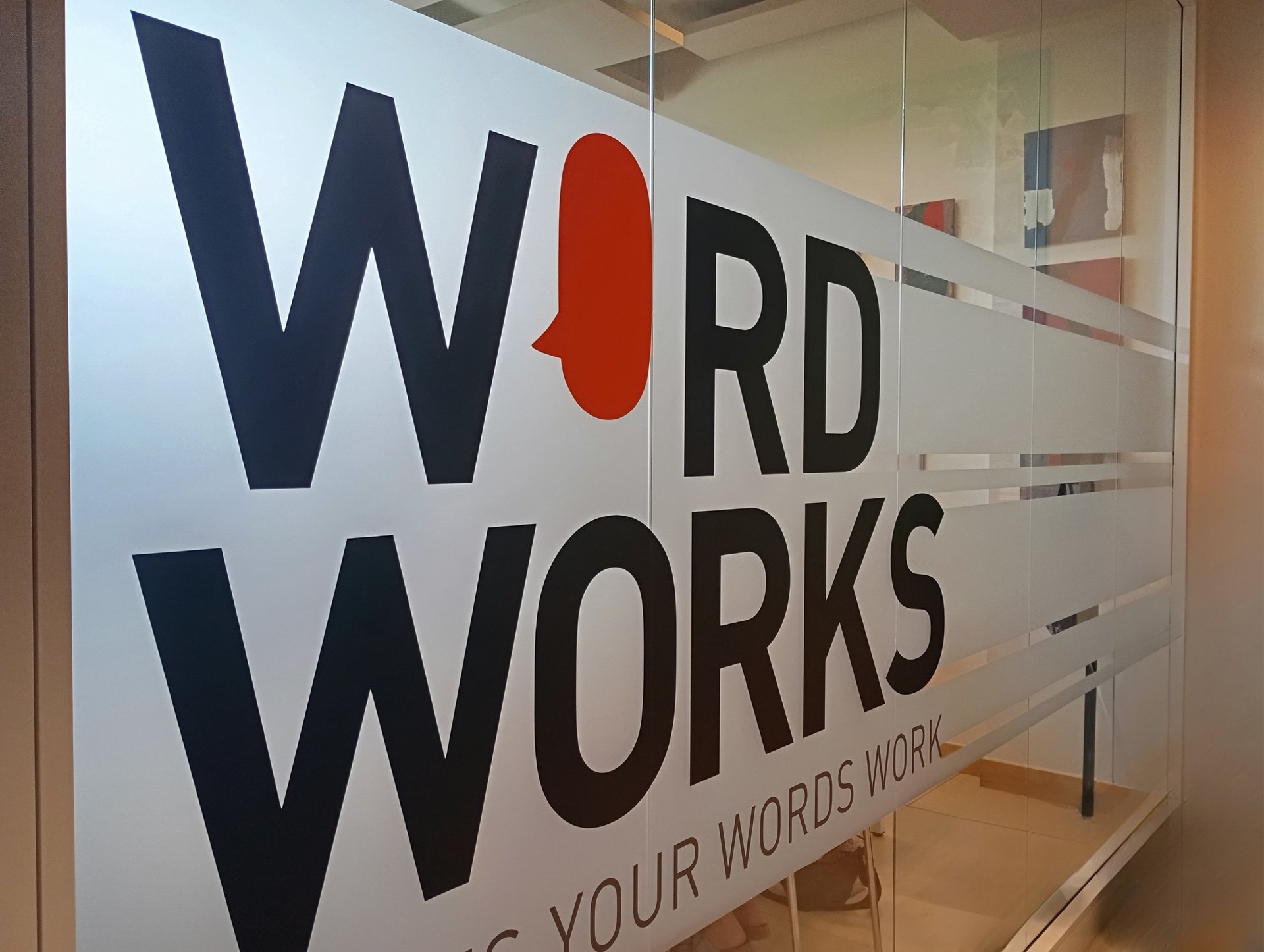 men and women sitting and standing by the table looking happy while staring at laptop