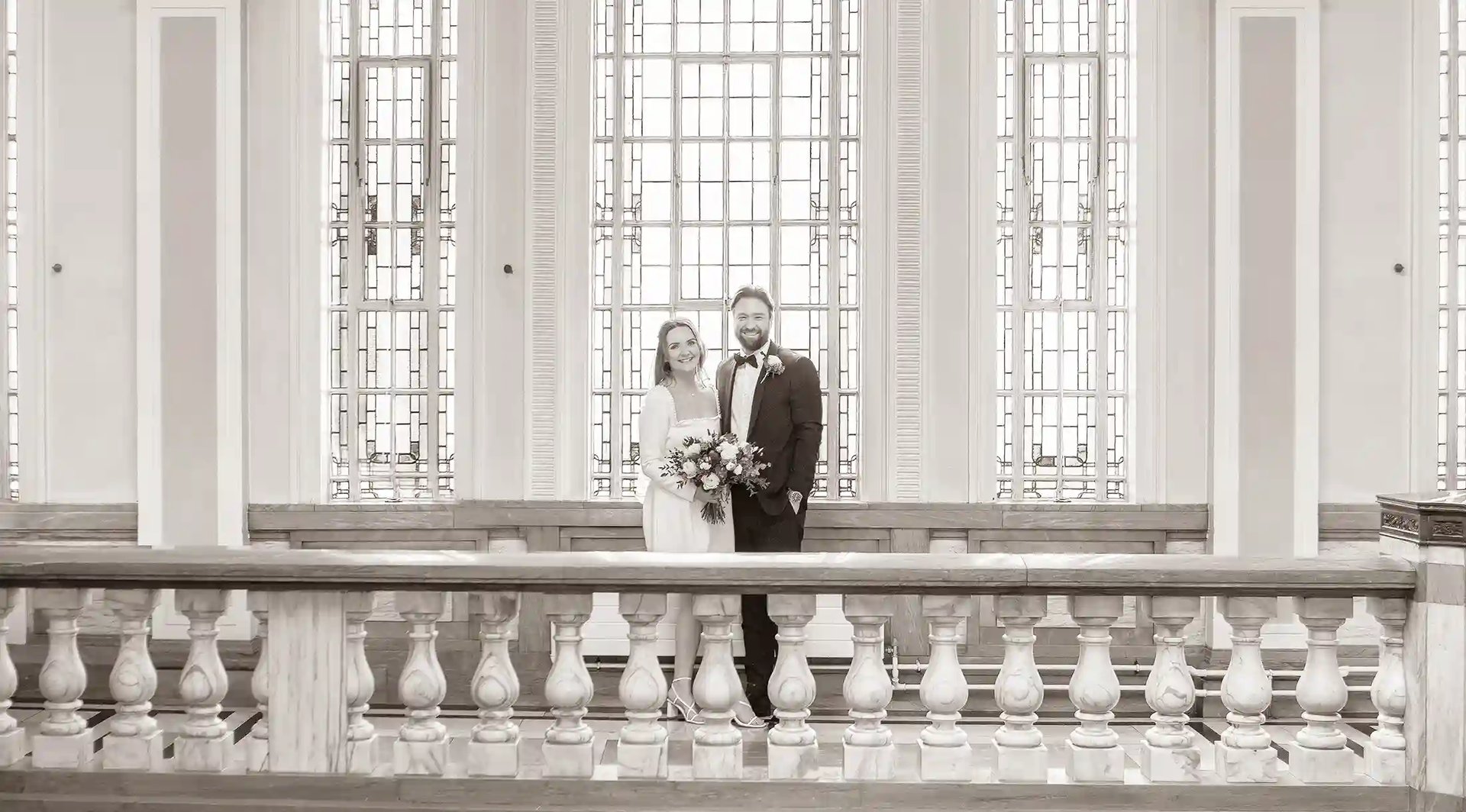 wedding couple standing in front of the large windows in Islington Town Hall