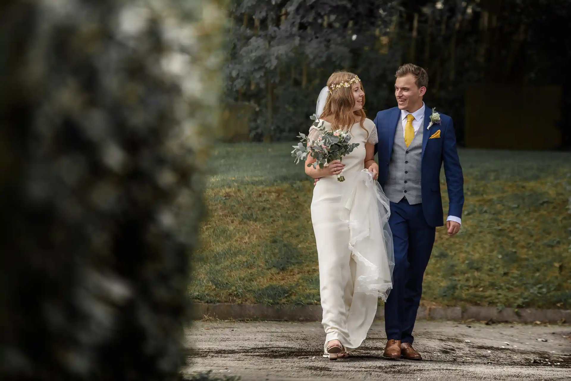A smiling bride and groom walking together outdoors after their wedding ceremony.