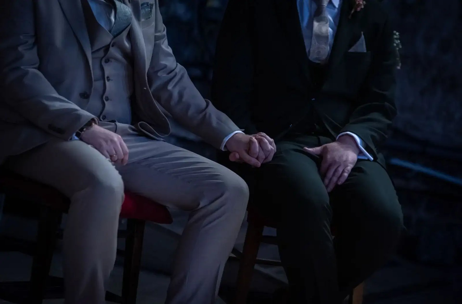 two grooms sitting holding hands