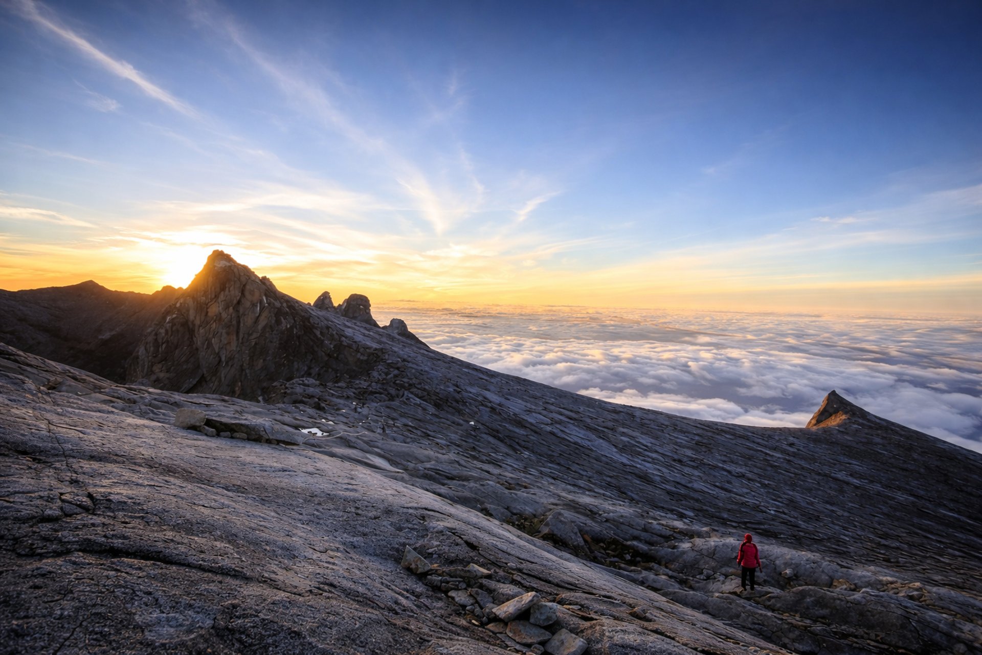 a view of the top of a mountain with clouds below