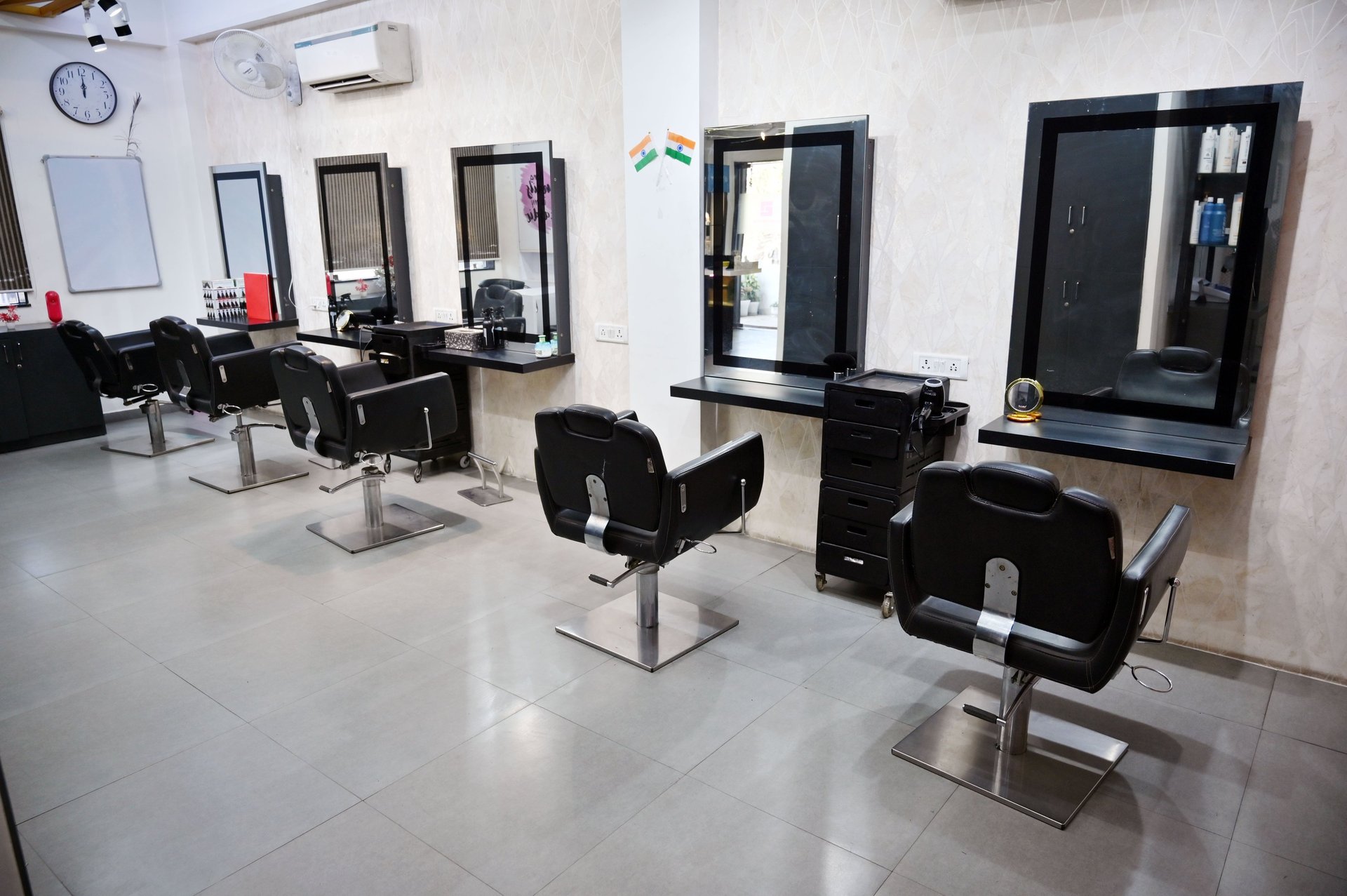grayscale photo of woman using laptop near three salon chairs