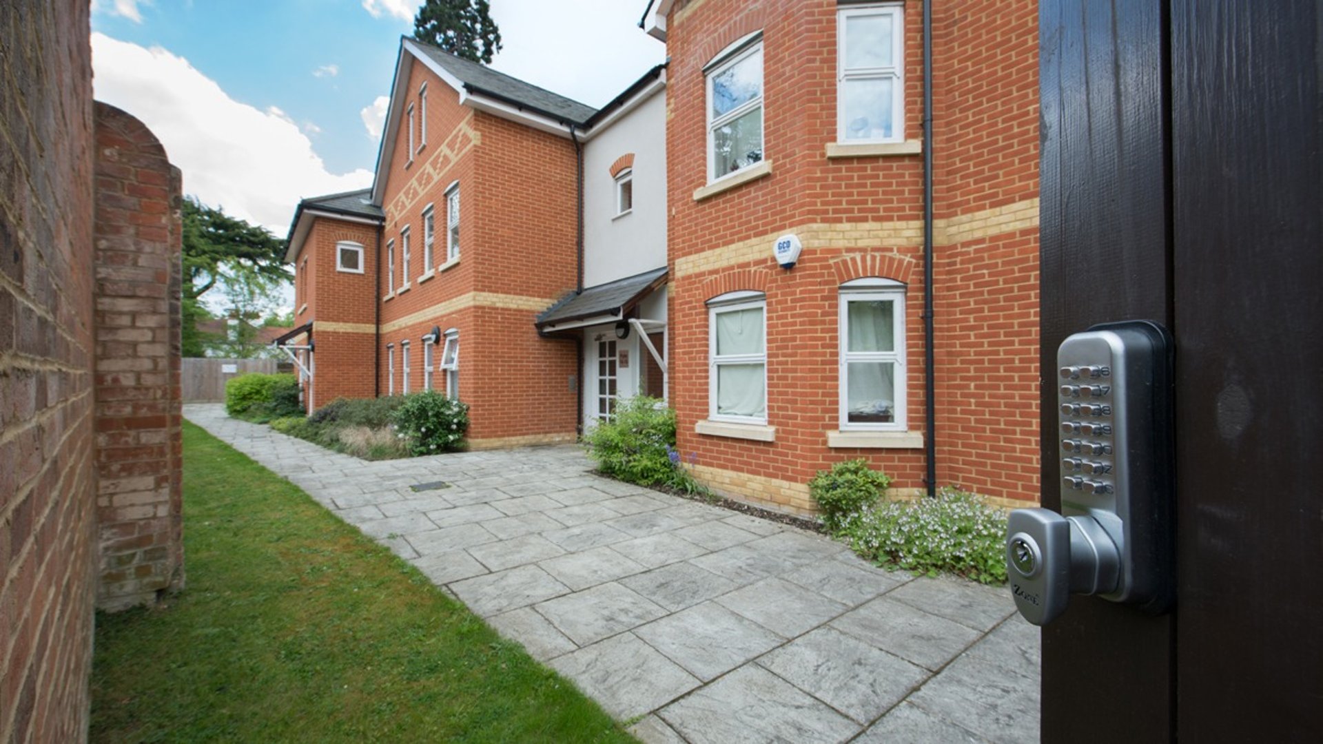 A low rise, smart apartment block surrounding three sides of courtyerd with with attractive planting and a water feature, 