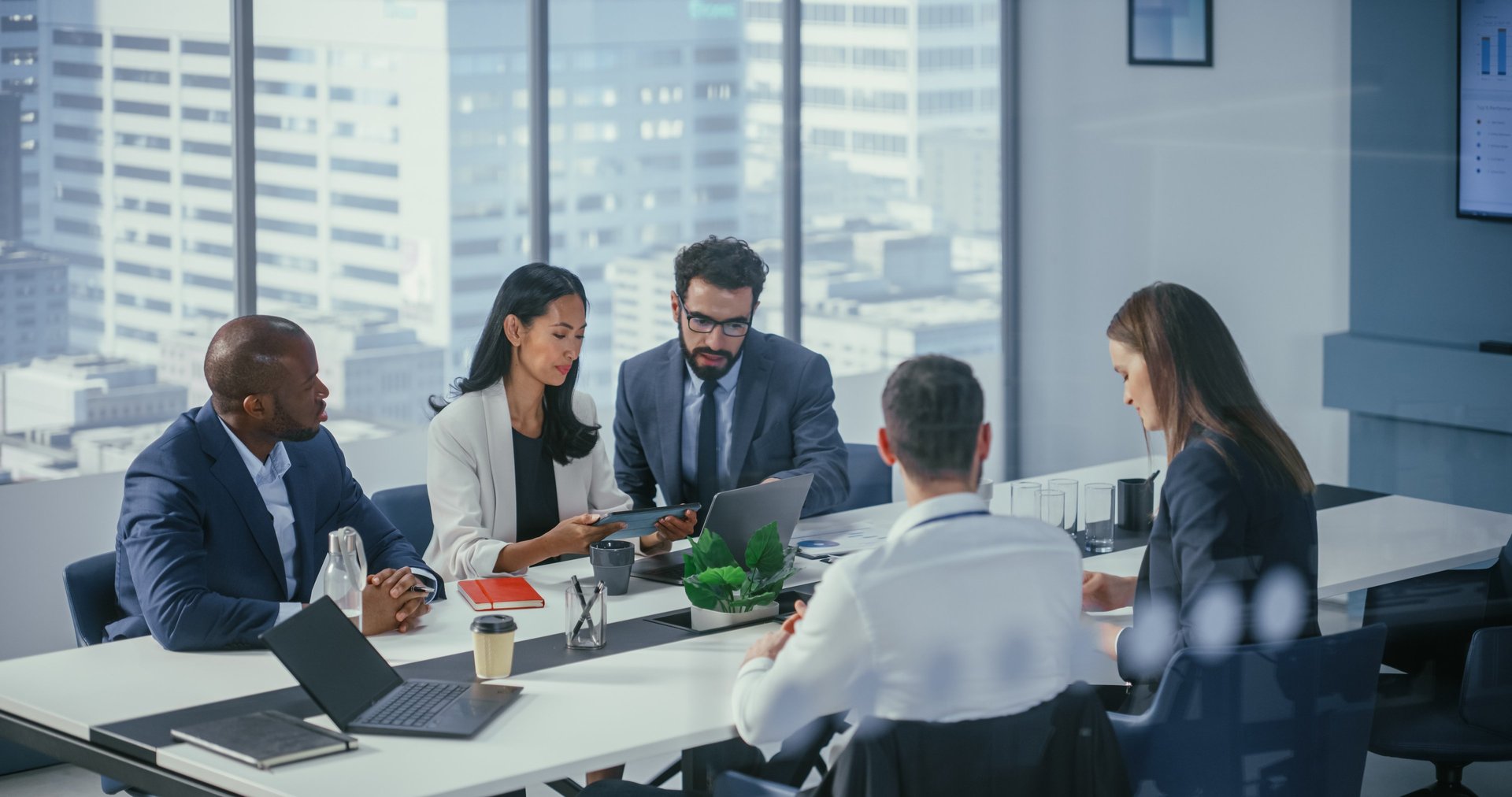 Professional men and women sit around a boardroom table to have a meeting