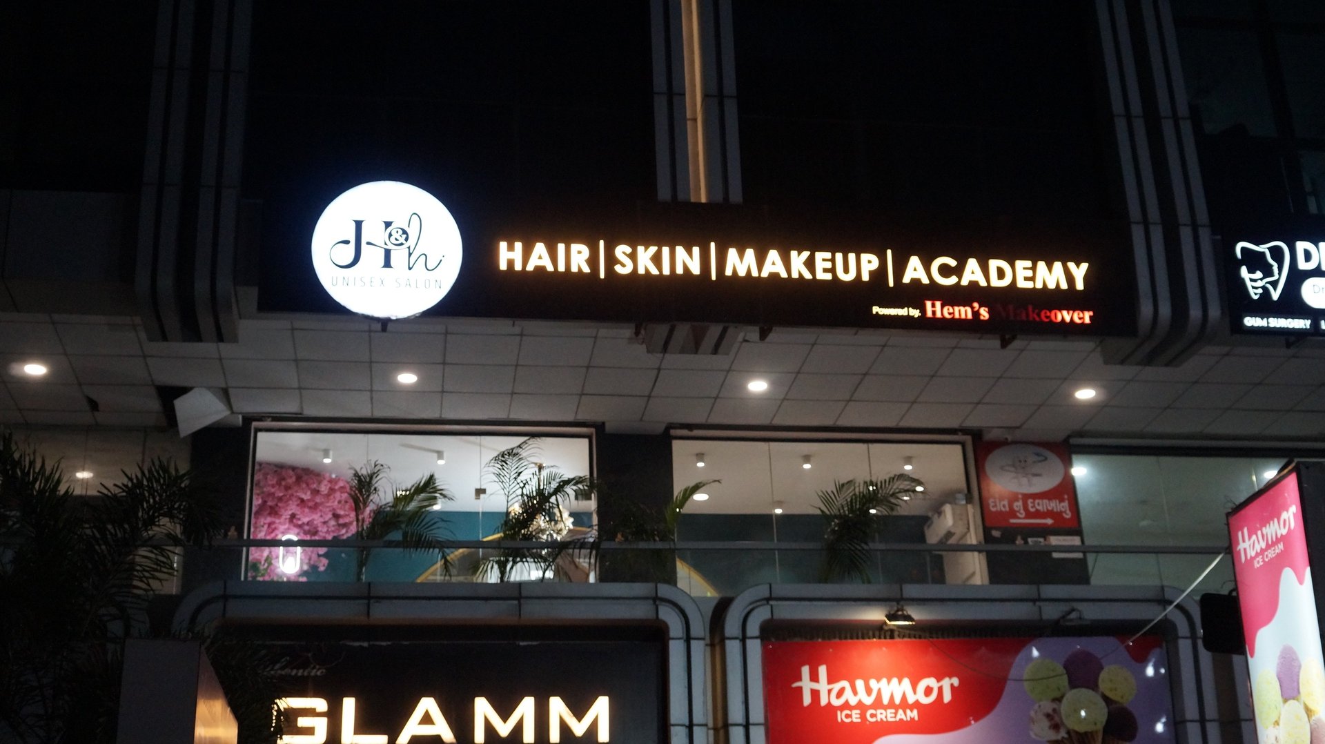 grayscale photo of woman using laptop near three salon chairs