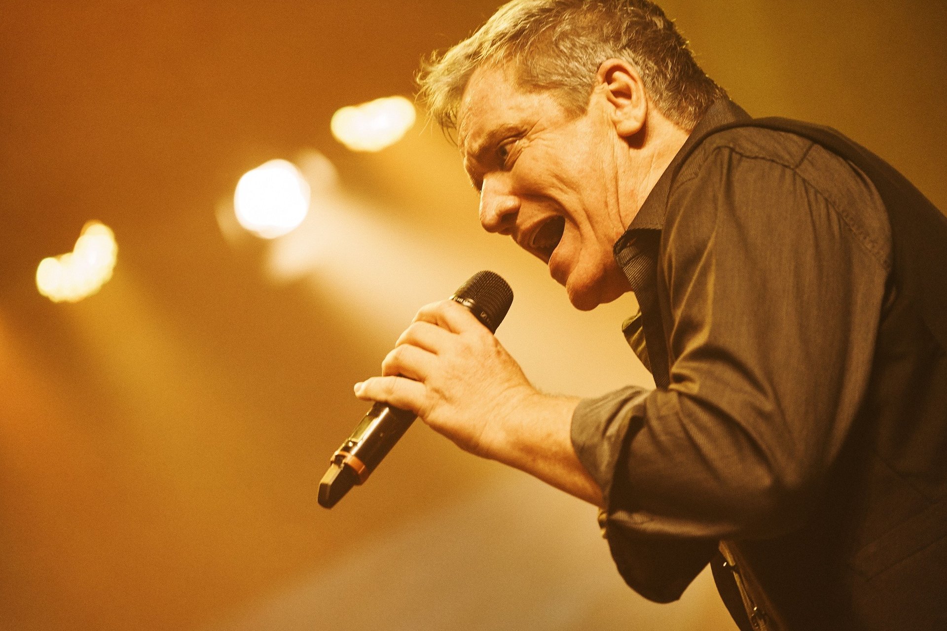 Silhouette of a person singing into a microphone