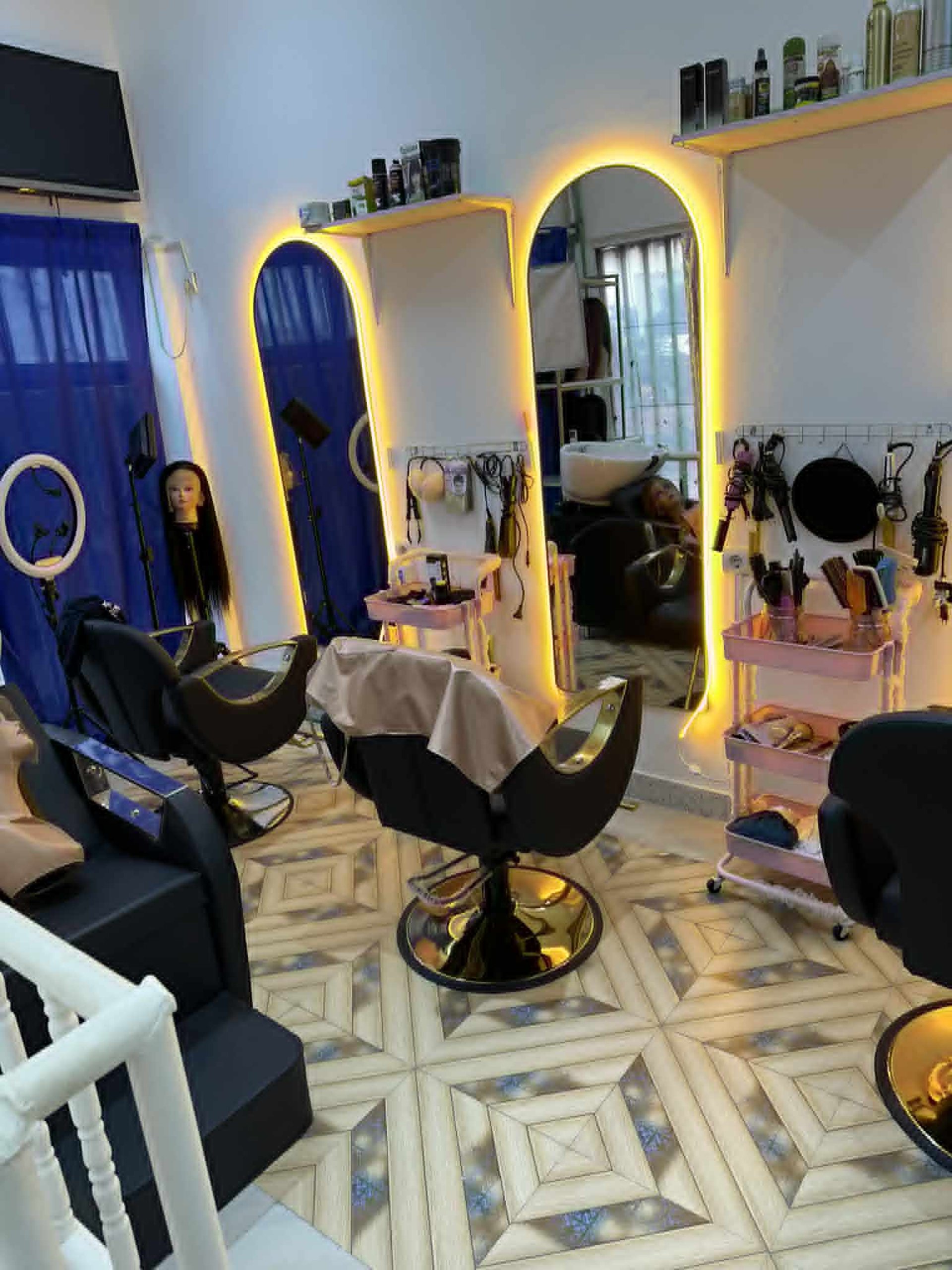 Área interna de salão de beleza profissional com cadeiras e espelhos iluminados