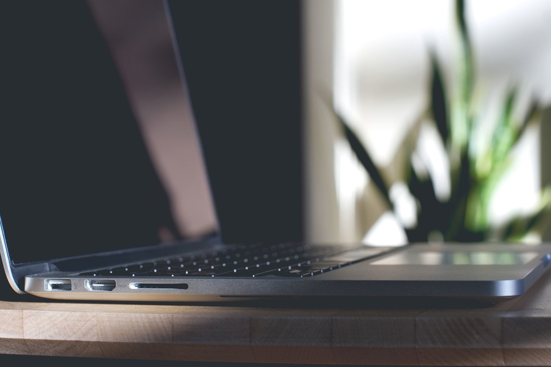 white ceramic mug beside macbook pro on brown wooden table