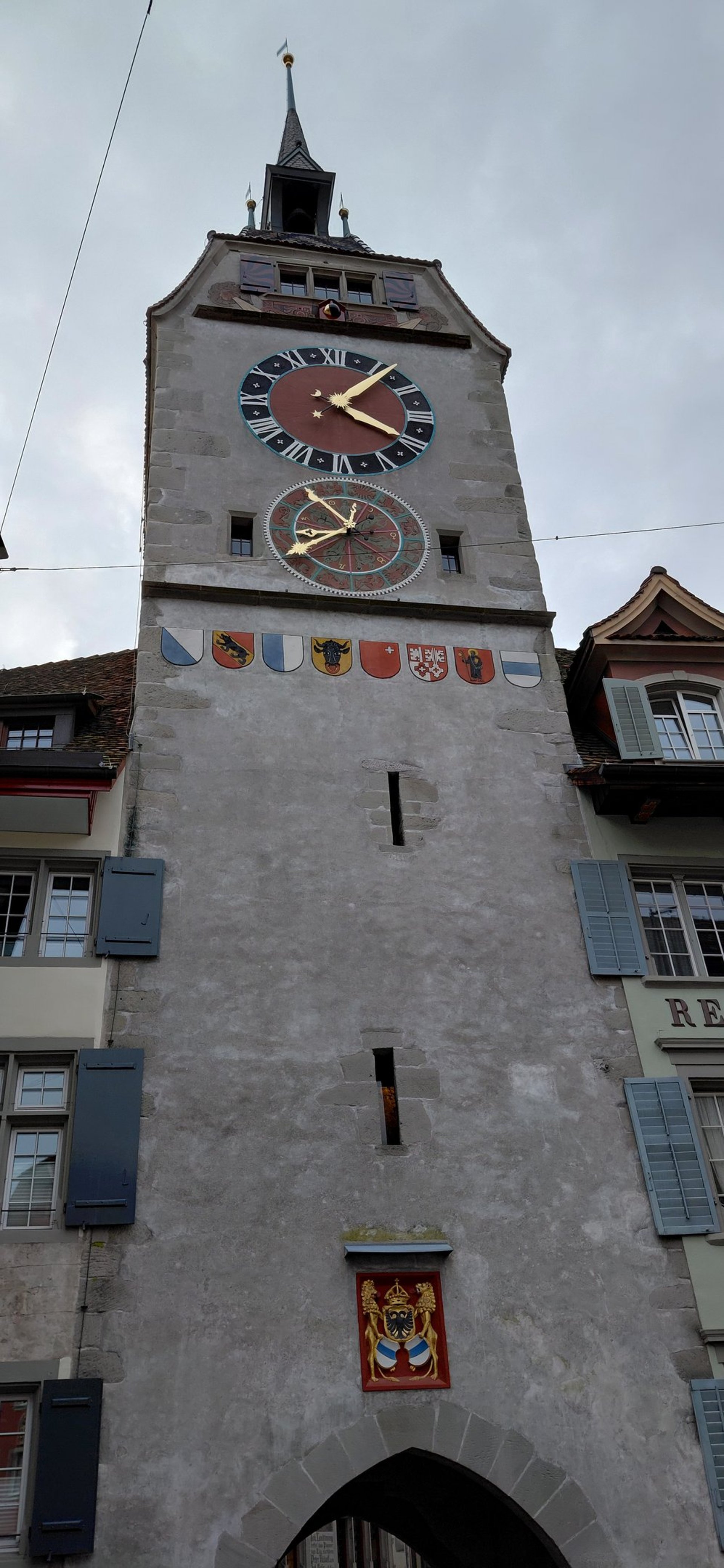 A clock tower with blue and white striped flags.