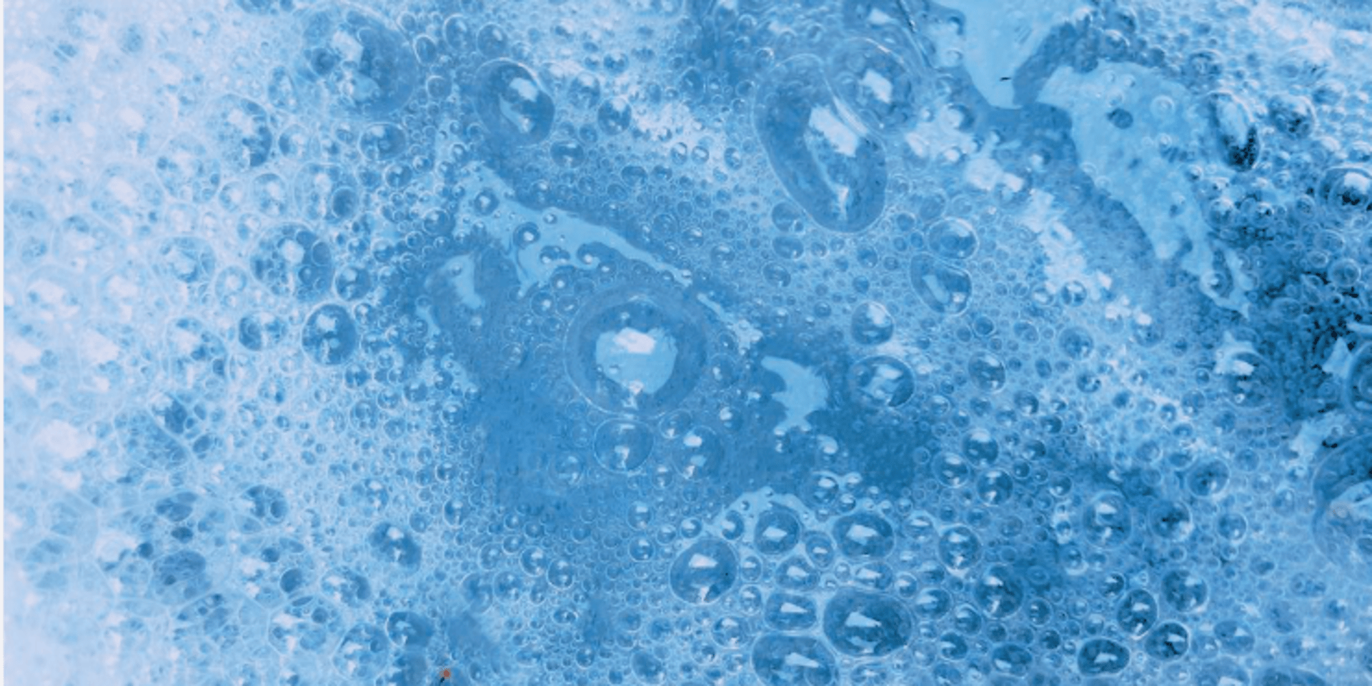 person holding blue textile near clear glass bottle