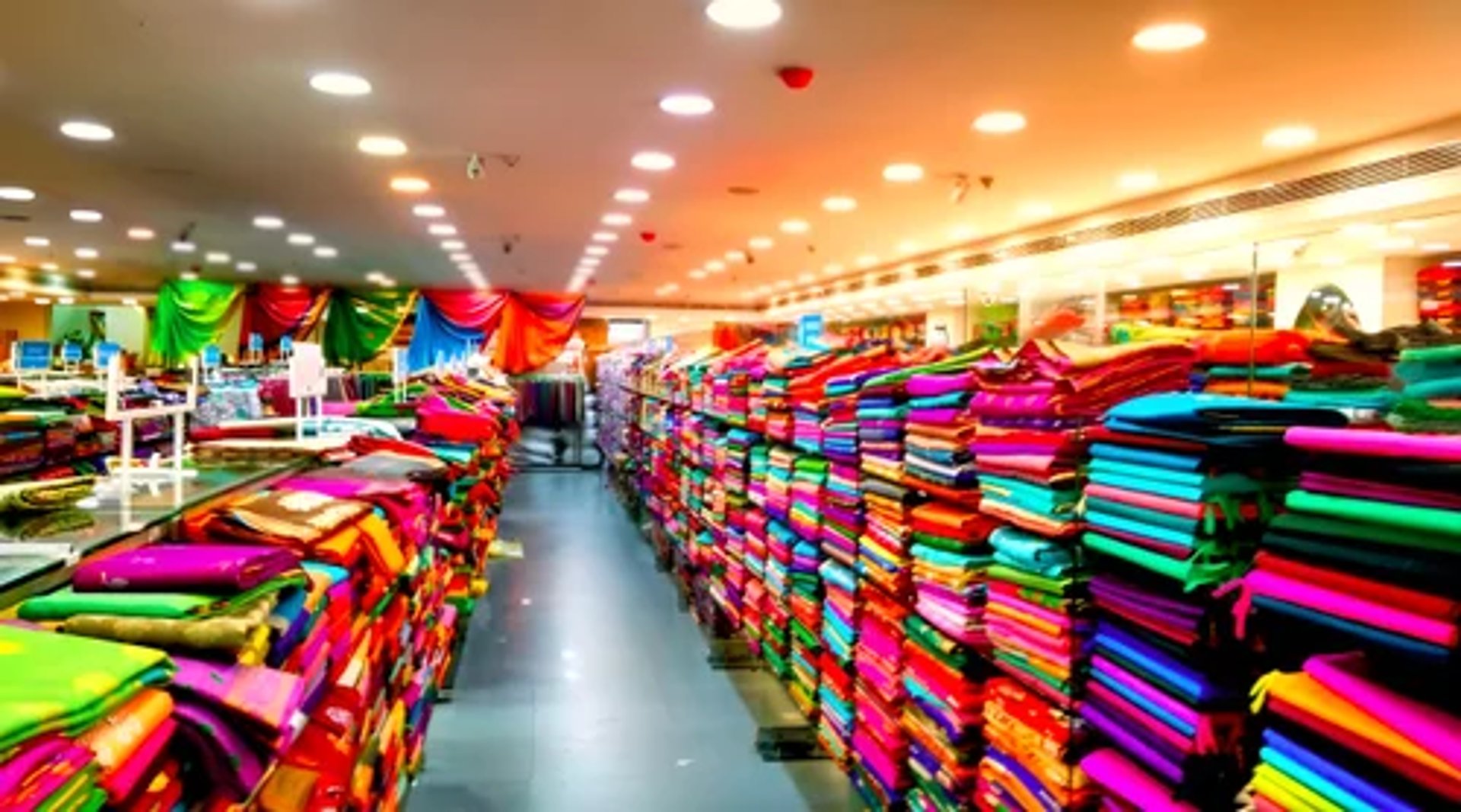 a bunch of different colored fabrics hanging on a wall