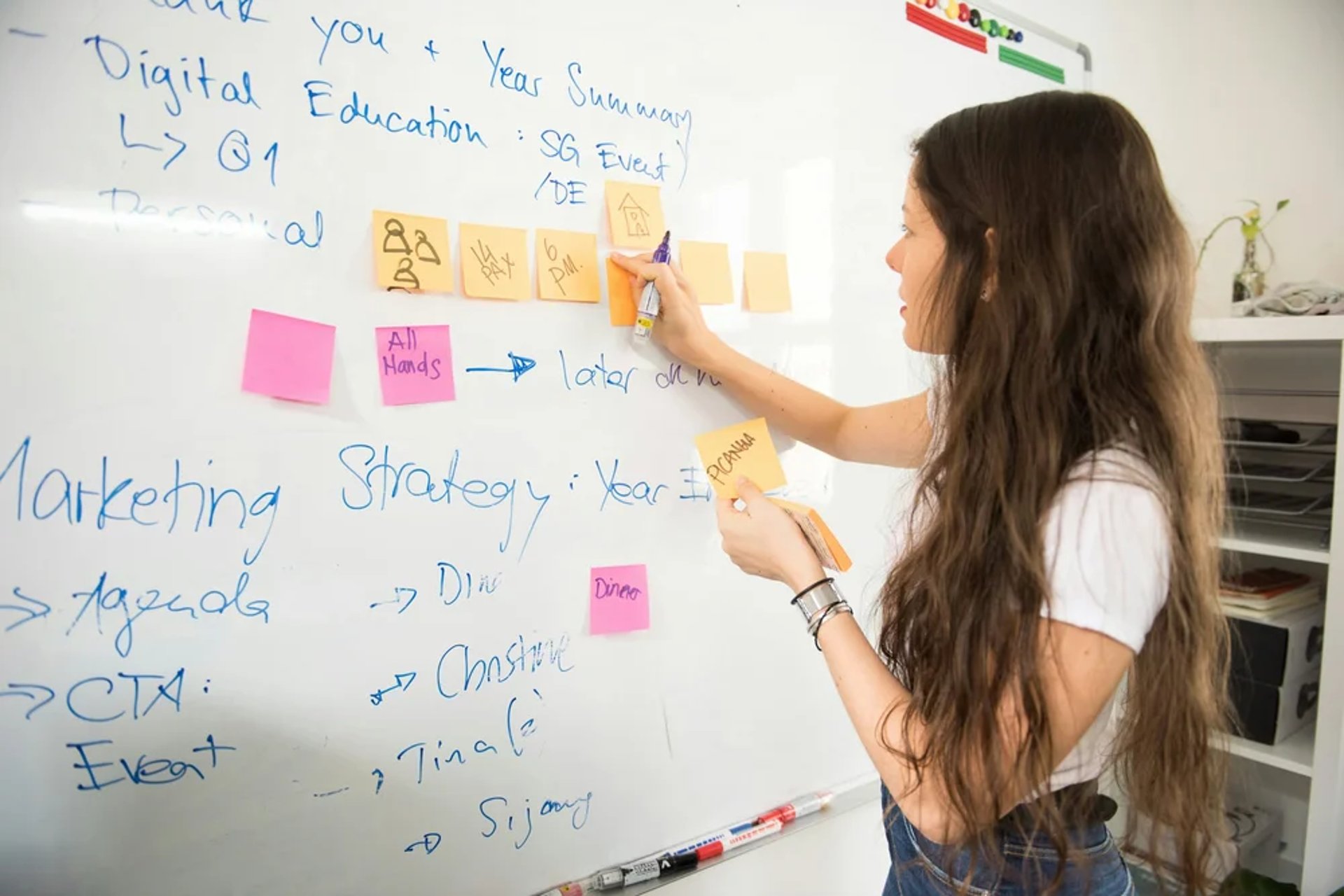Woman writing on sticky notes on a wall.