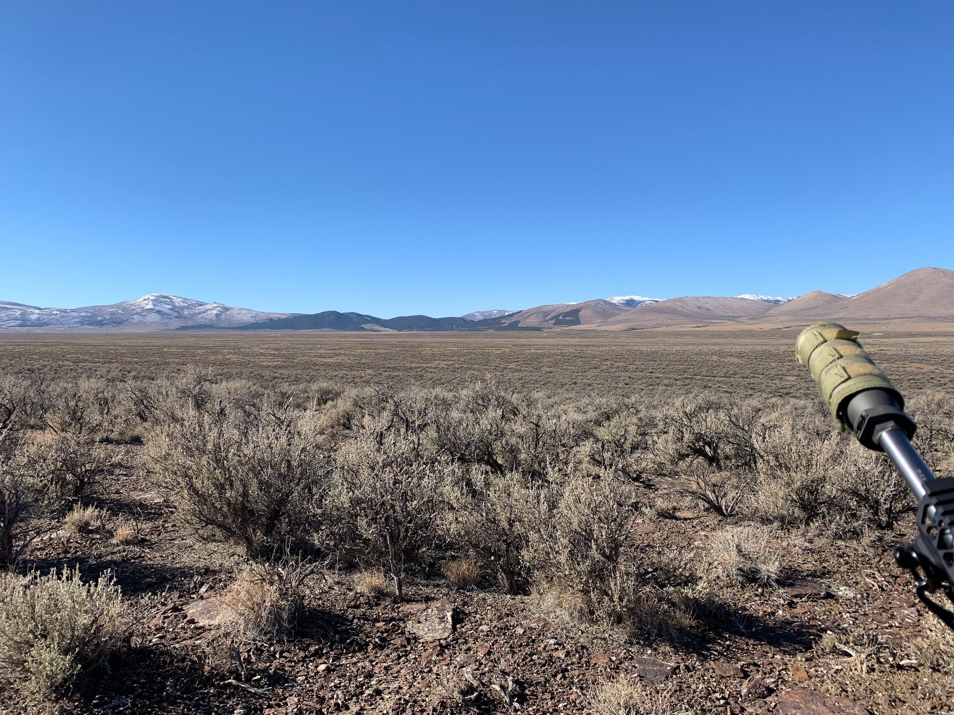 brown grass field near mountains under white clouds and blue sky during daytime