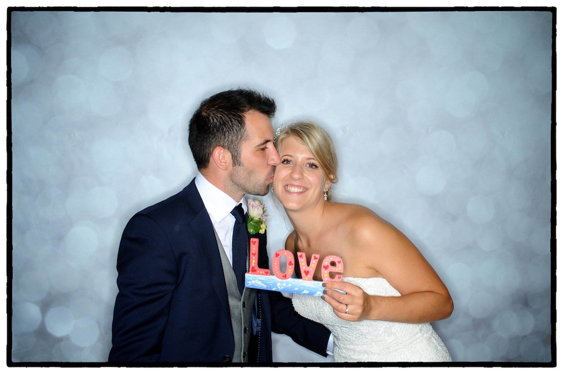 mariés souriant avec accessoires dans un photobooth