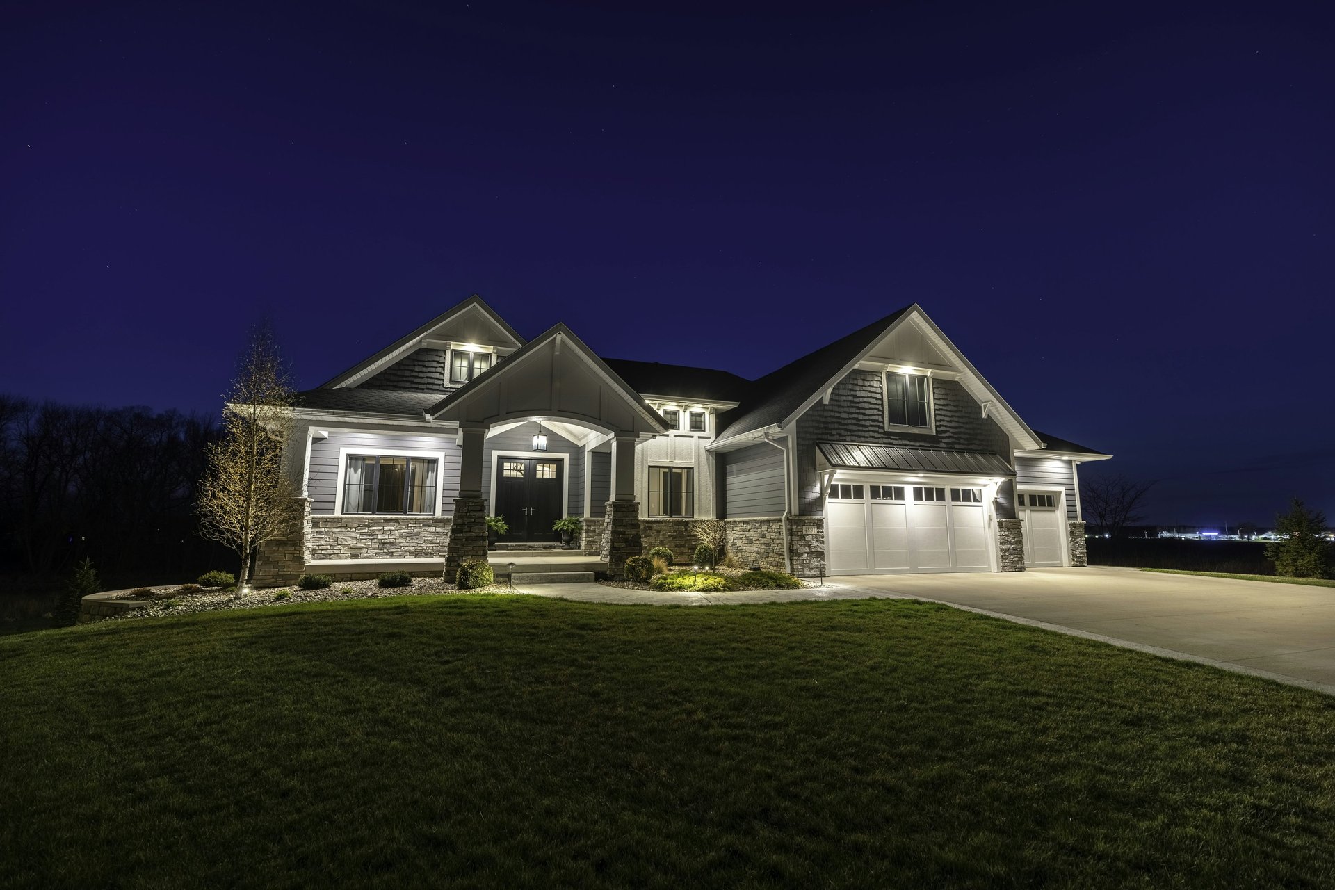 Illuminated custom home exterior at night in Kane County, built by Built to Last Custom Homes