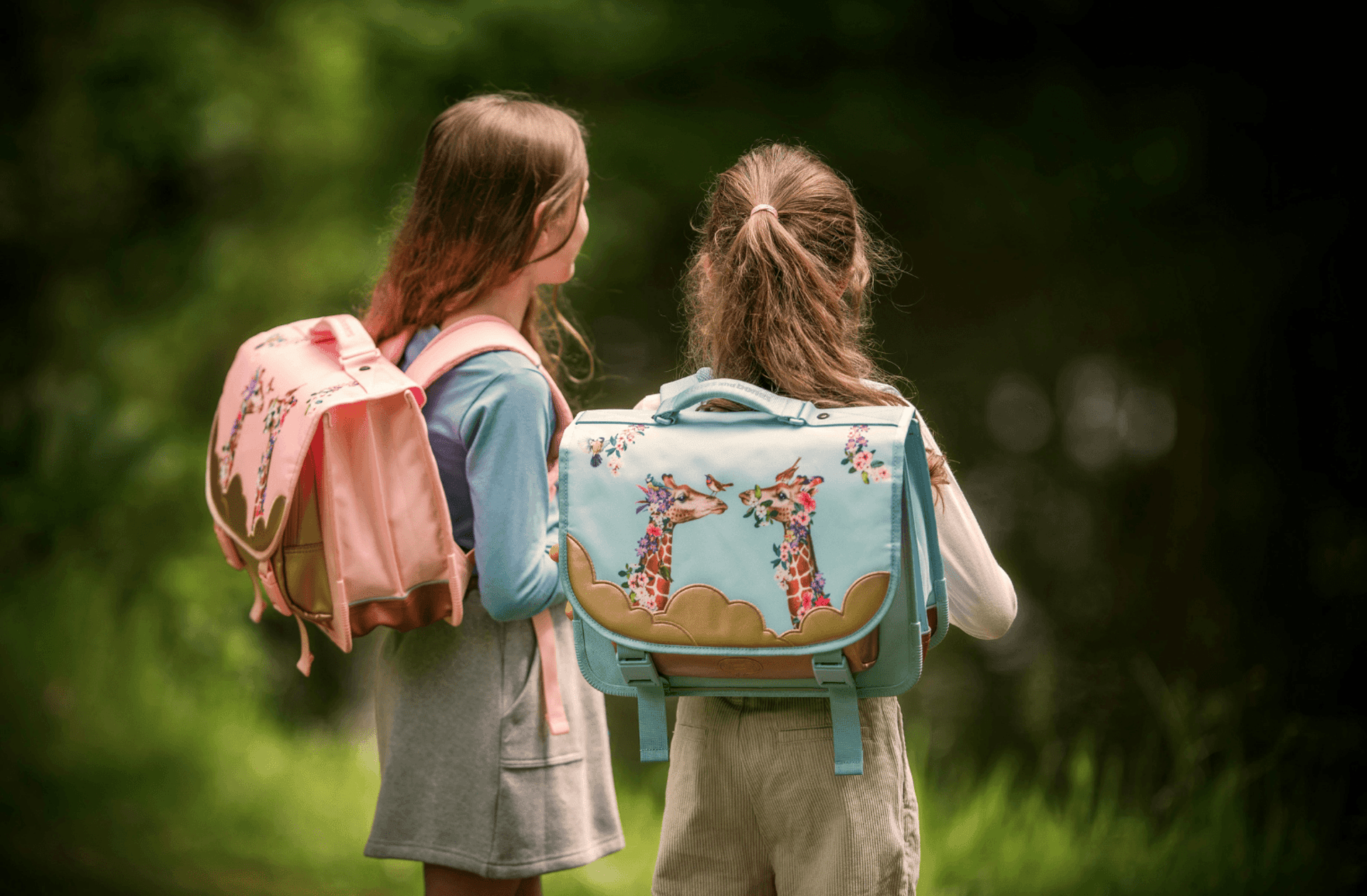 Two girls stand with their backpacks near water.