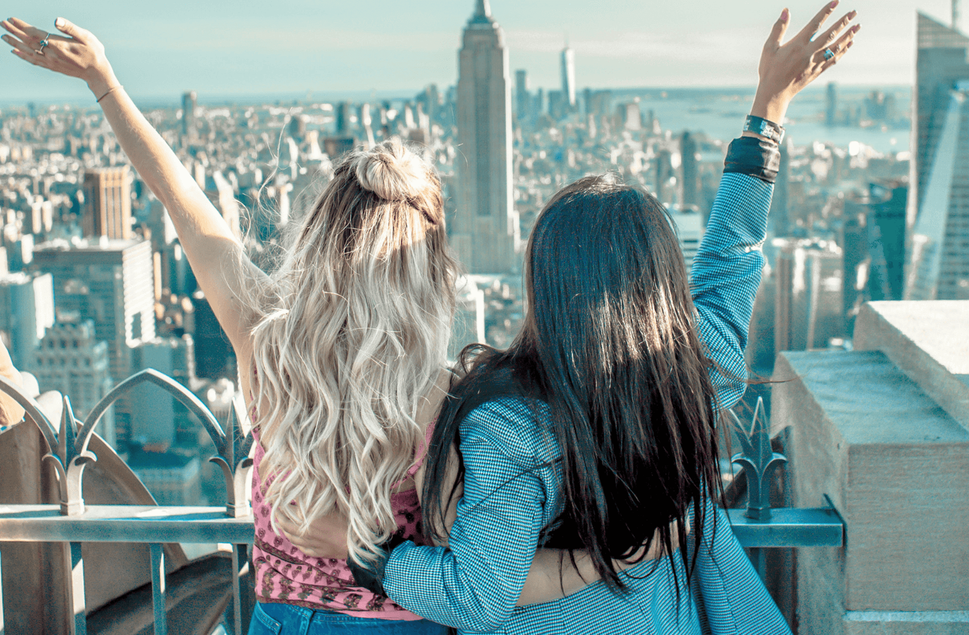 two women hands on their back while raising their hands facing Empire State building
