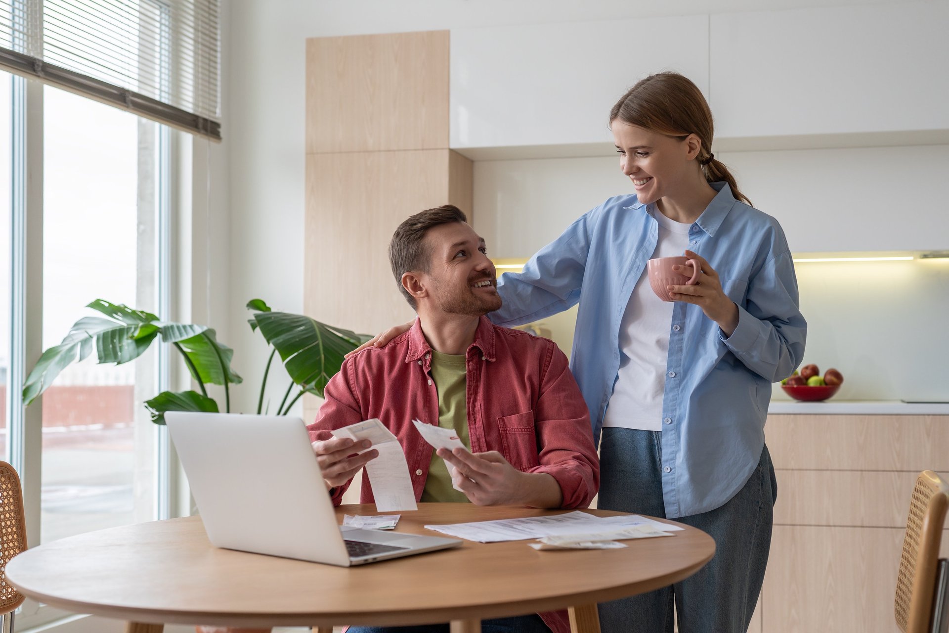 Couple looking stressed over bills at kitchen table.