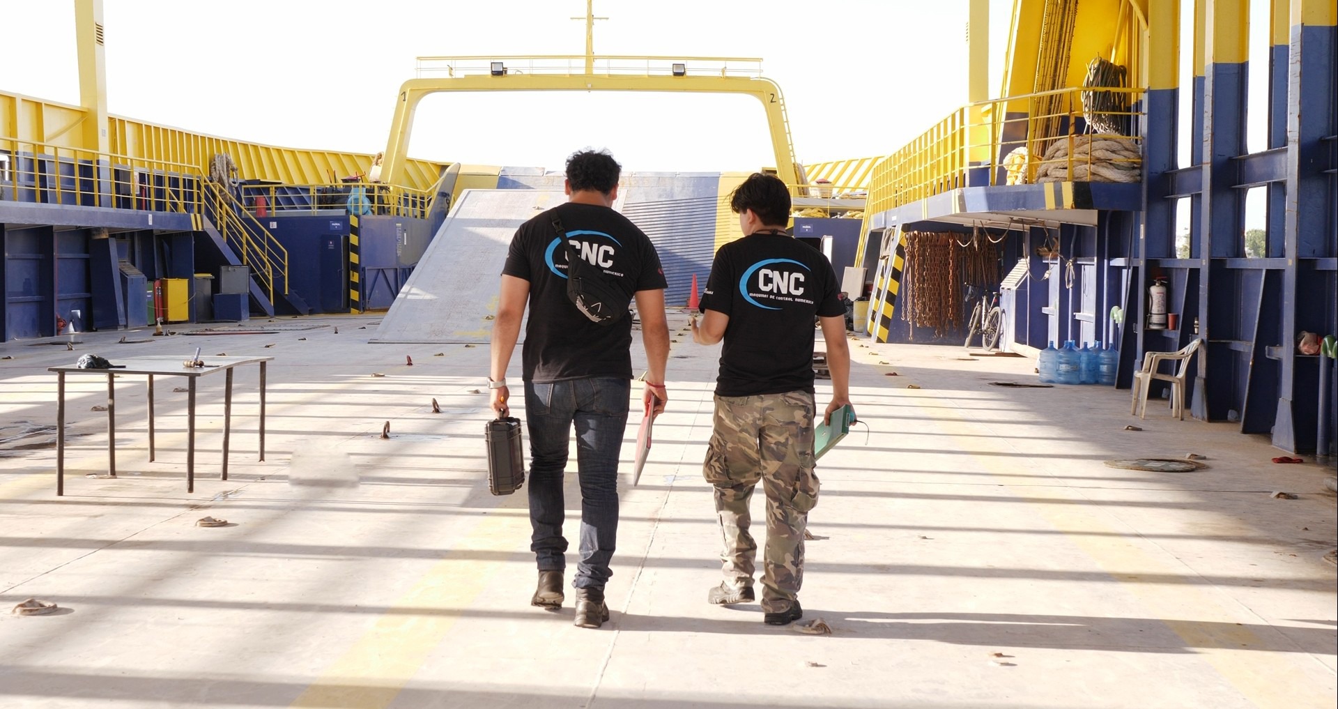 Workers in hard hats repair large industrial machinery gears.