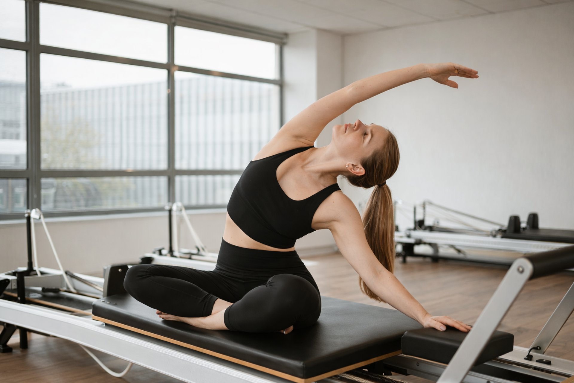 Woman does pilates exercise on a reformer machine.