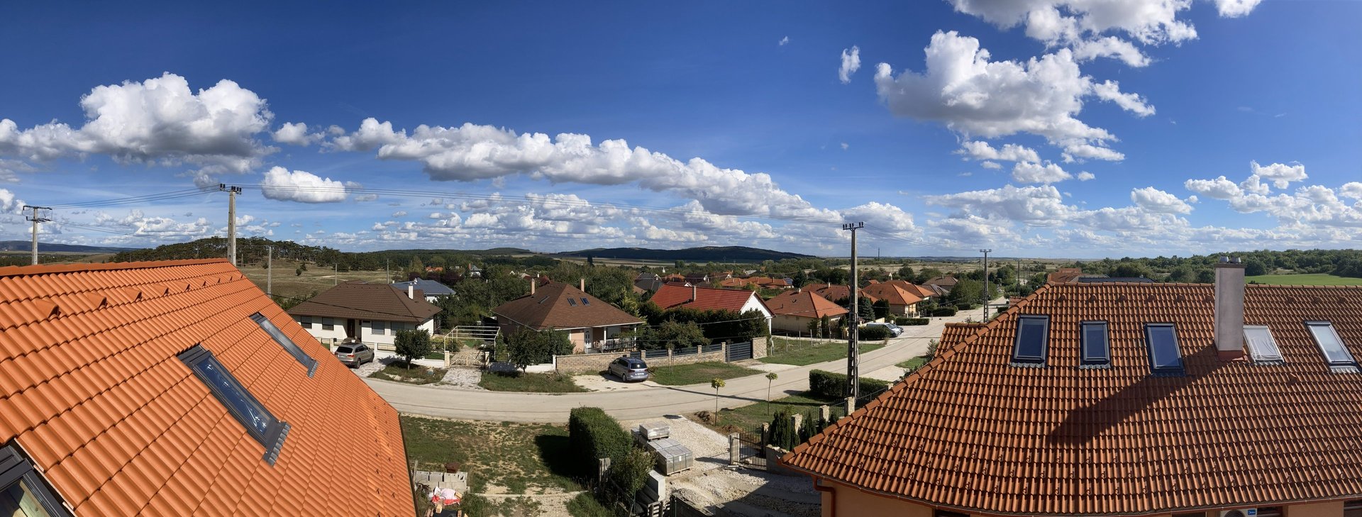 Kertvárosi utca és házak egy háztetőről nézve napos időben.