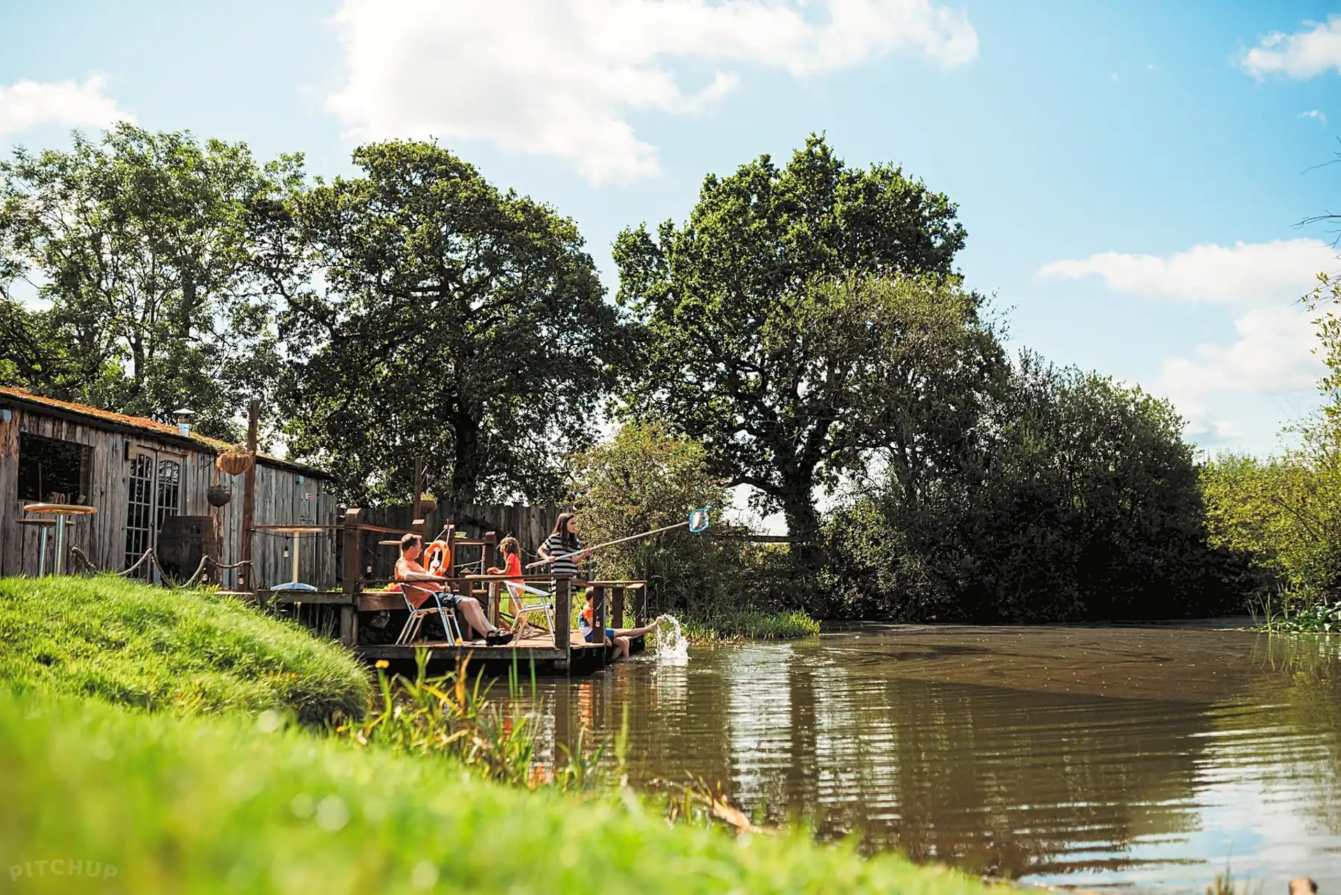 relaxing comunal area by the pond decking and firepit area in the background