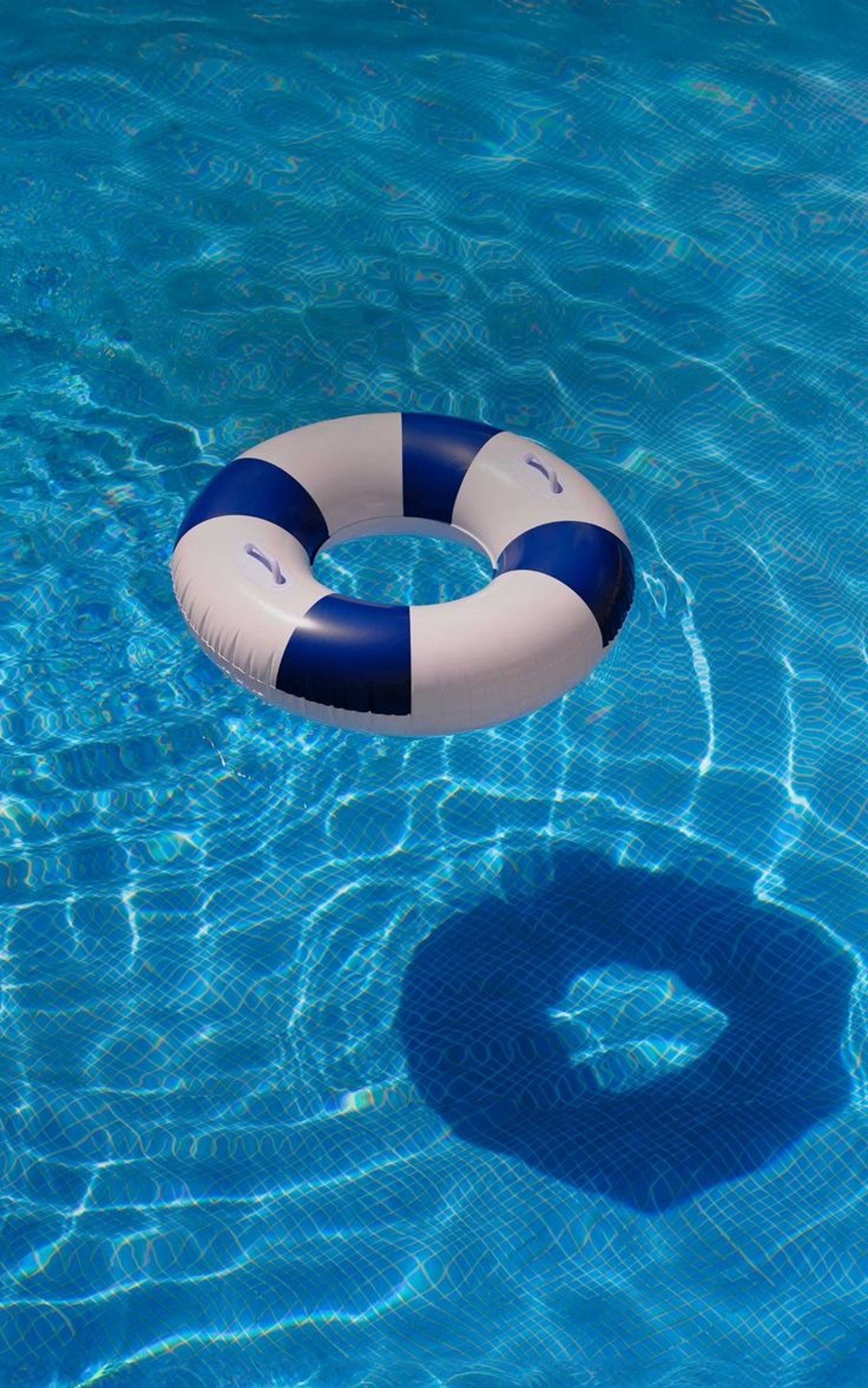 Two lounge chairs by a pool with inflatable toys.