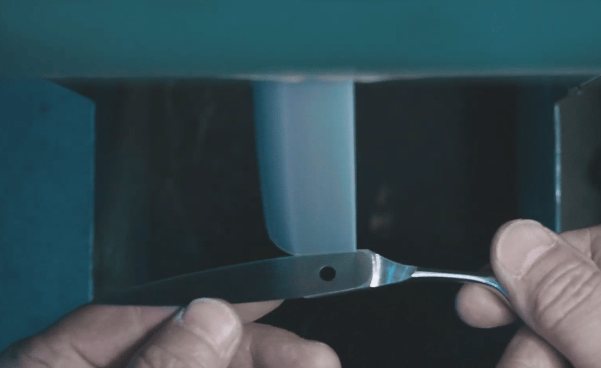 Proceso artesanal de afilado de cuchilla en rueda de amolar profesional, resaltando precisión y detalle en el taller.