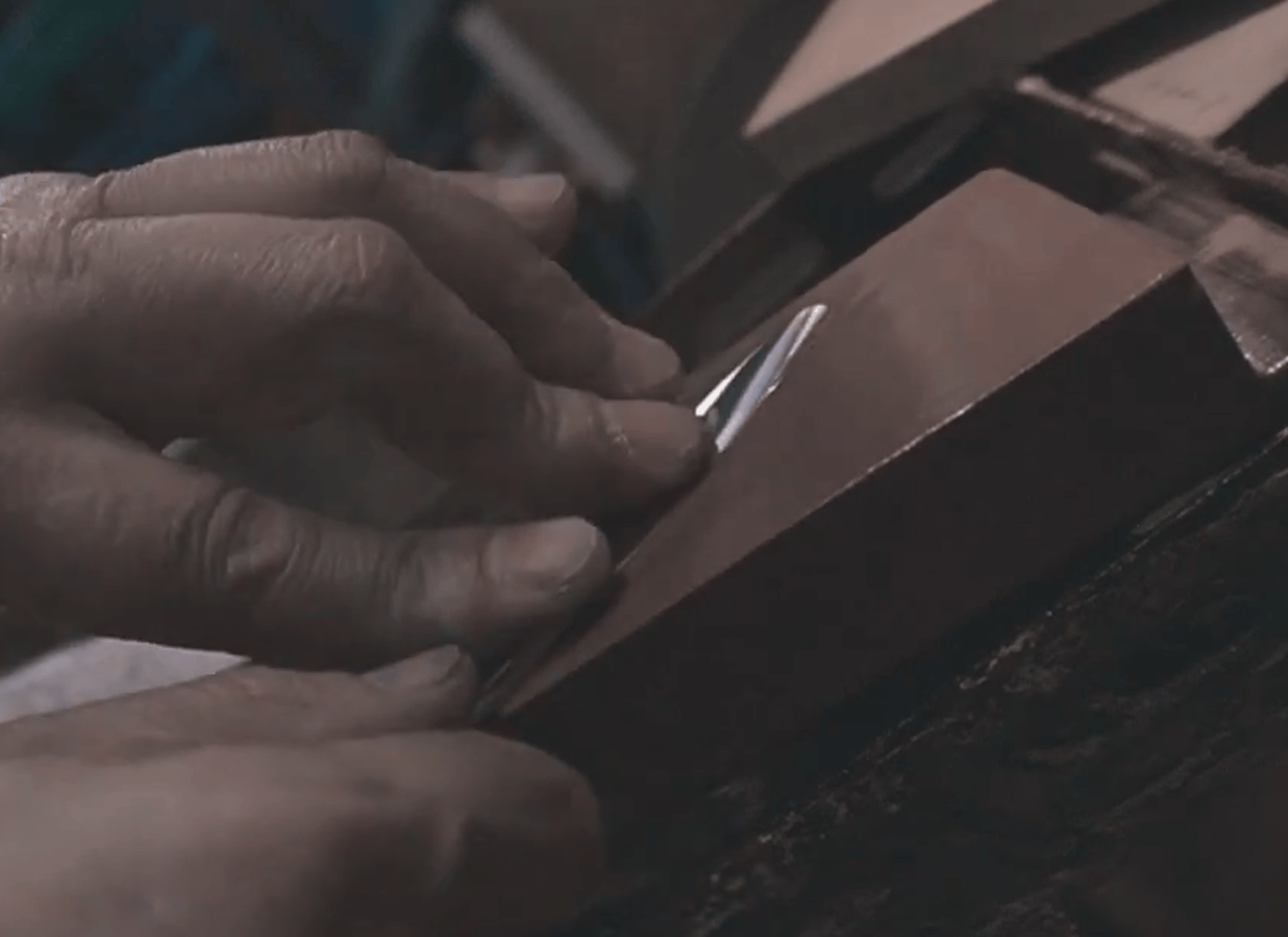 Artesano profesional amolando manualmente a tijeras profesionales de peluquería hecha a mano.