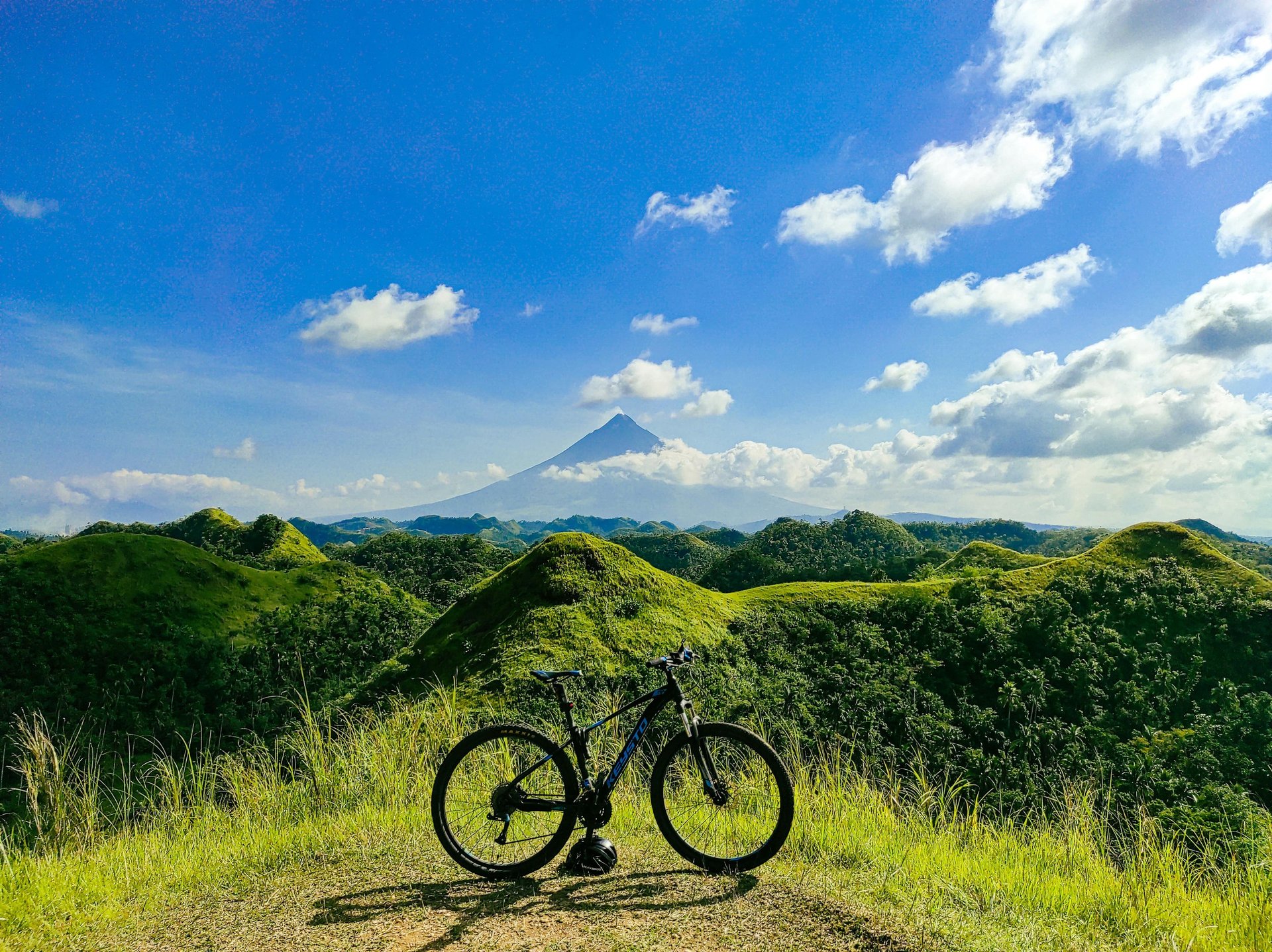 man holding bike while standing on gray mountain