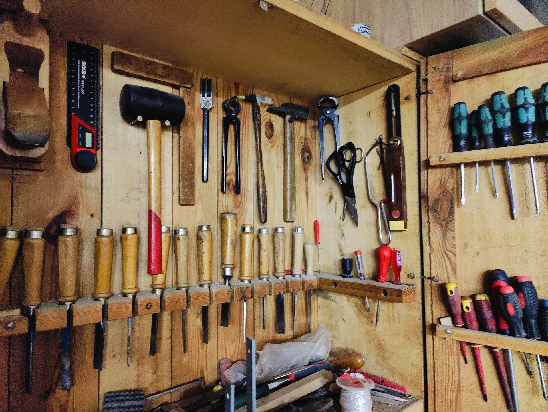 blue and black handle pliers beside brown wooden handle