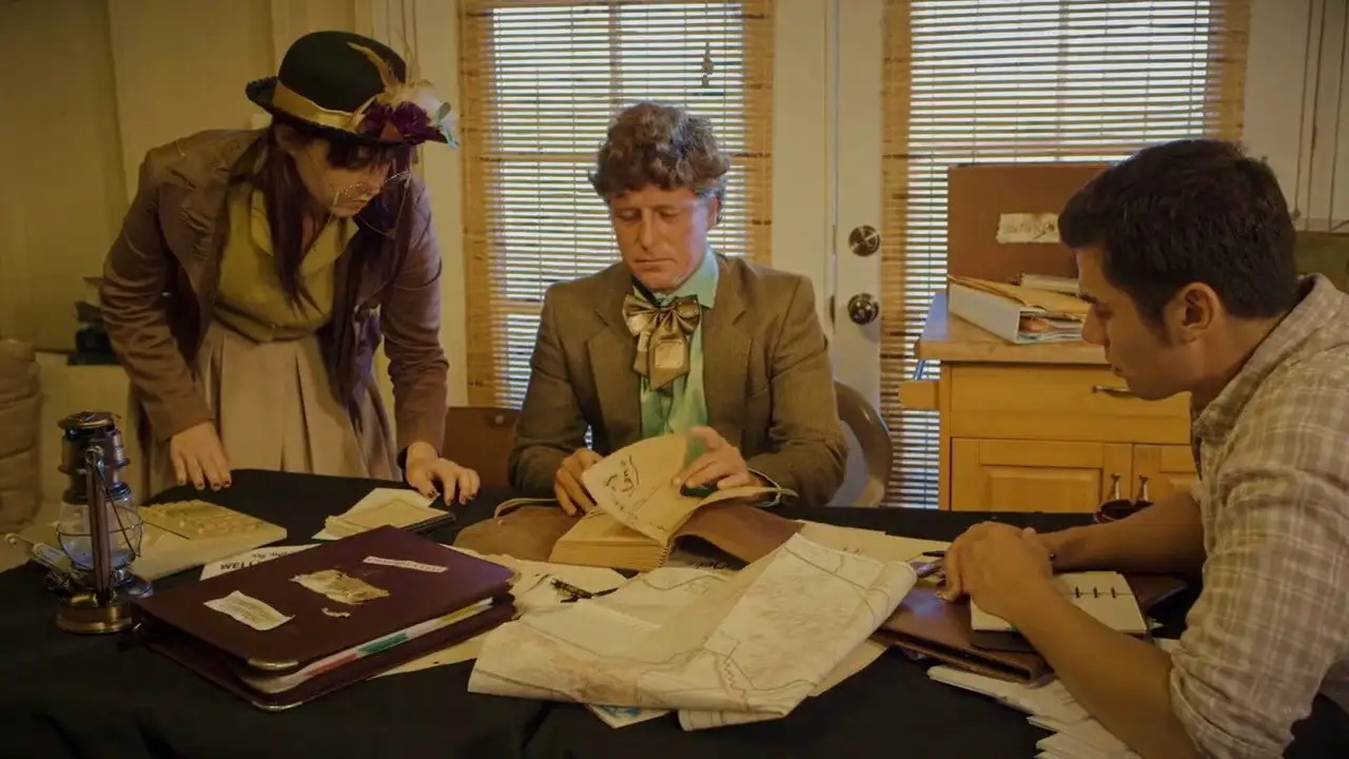 two men and woman looking at objects on a desk