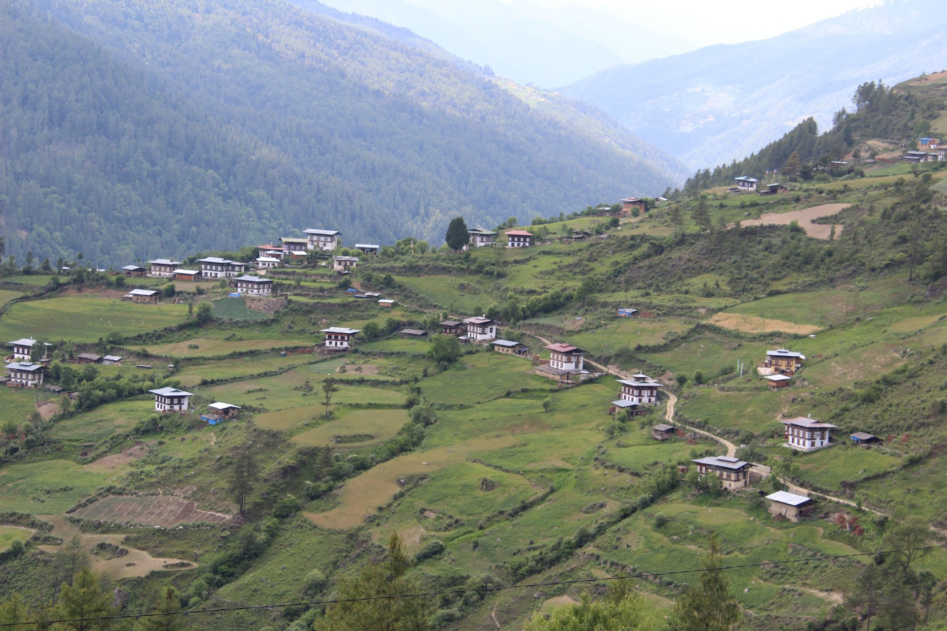 Car driving on a mountain road near traditional buildings.