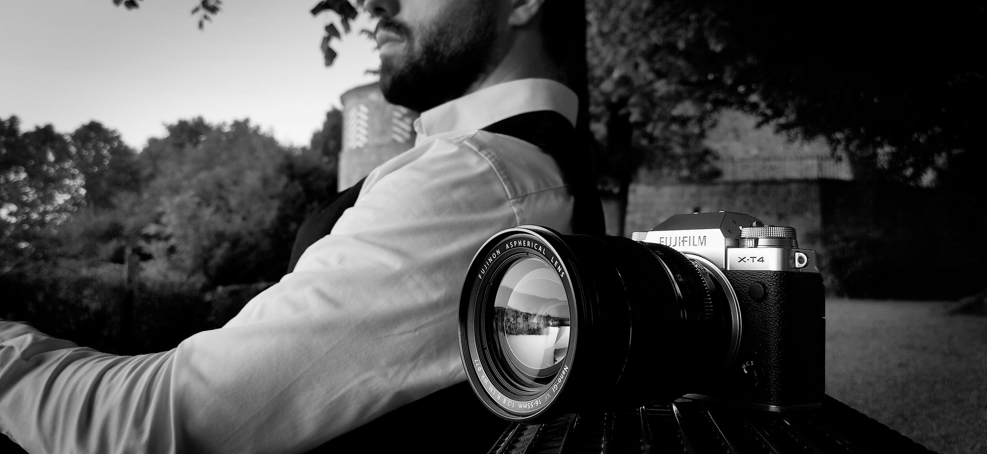 Vidéaste filmant depuis un banc en extérieur – prise de vue artistique en noir et blanc