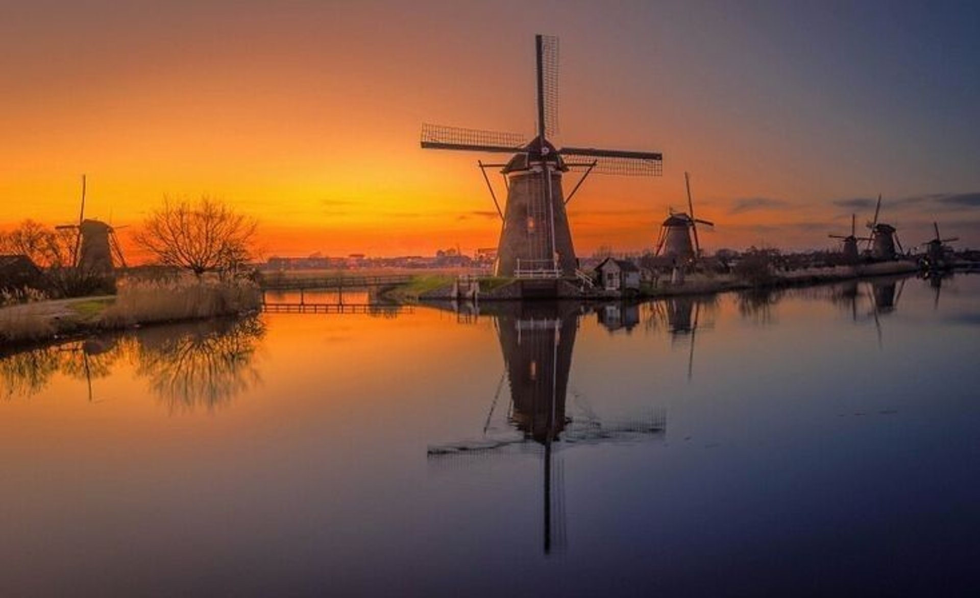 three windmills by the lake under grey cloudy sky