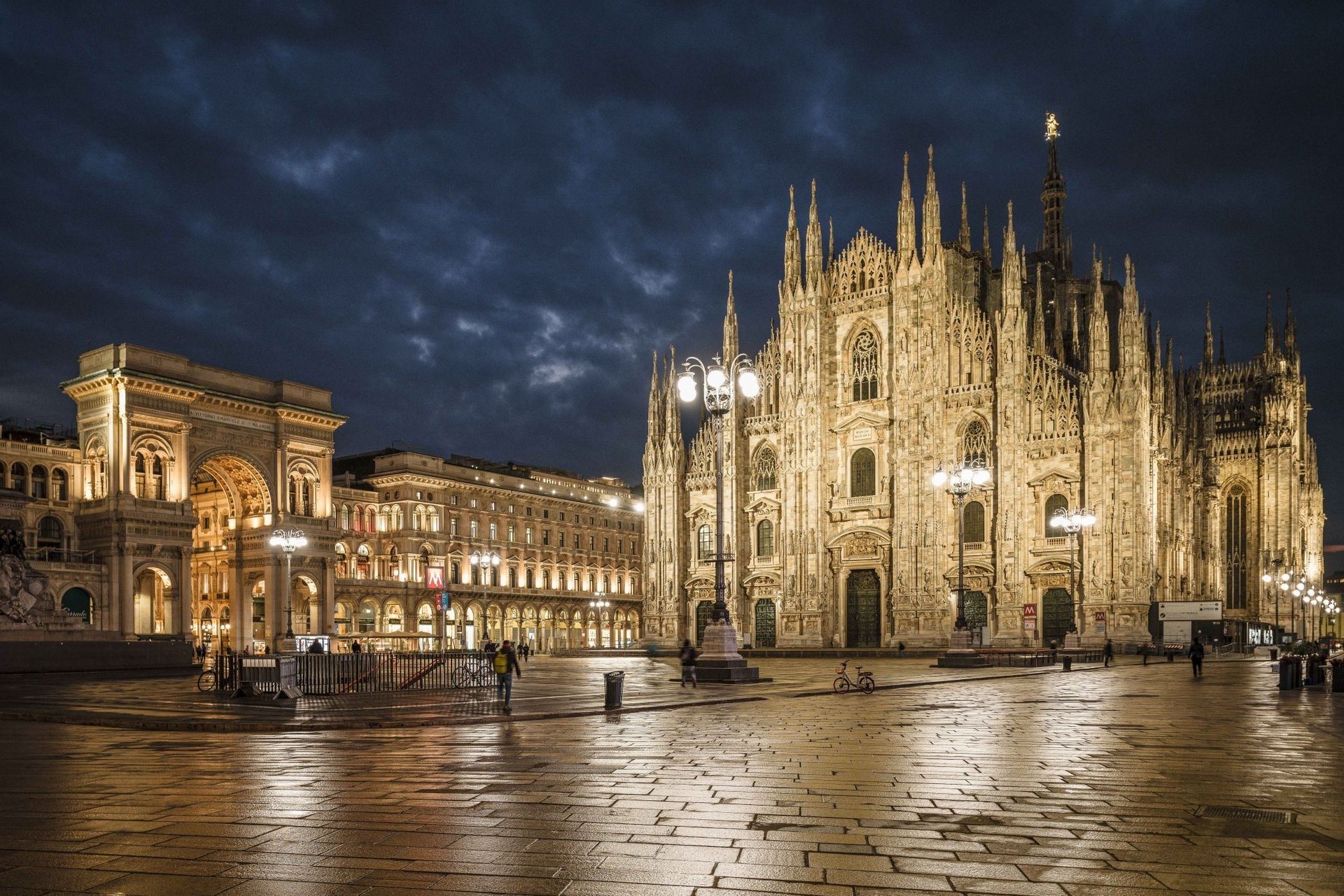 a cathedral lit up at night with people walking around