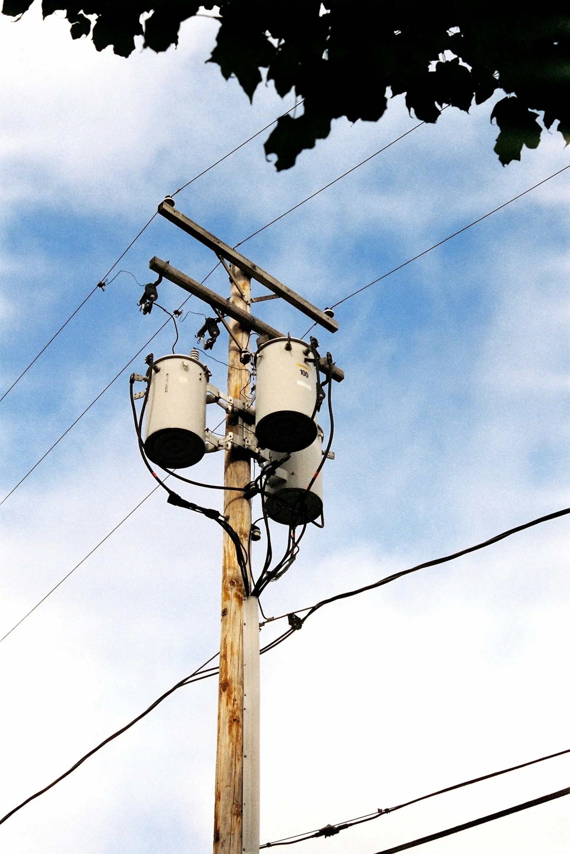 Utility pole with transformers and wires against sky.