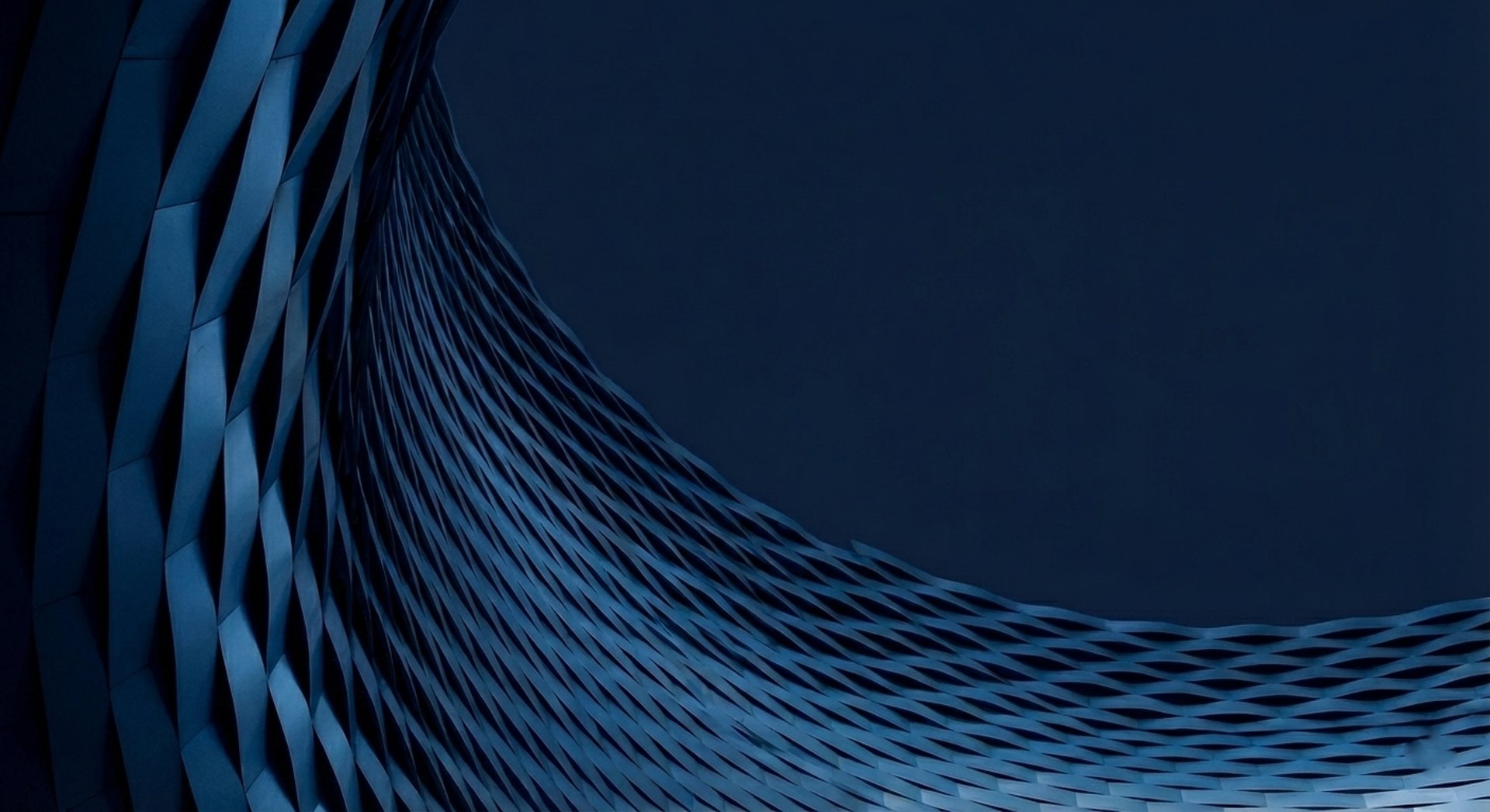 an abstract photo of a curved building with a blue sky in the background