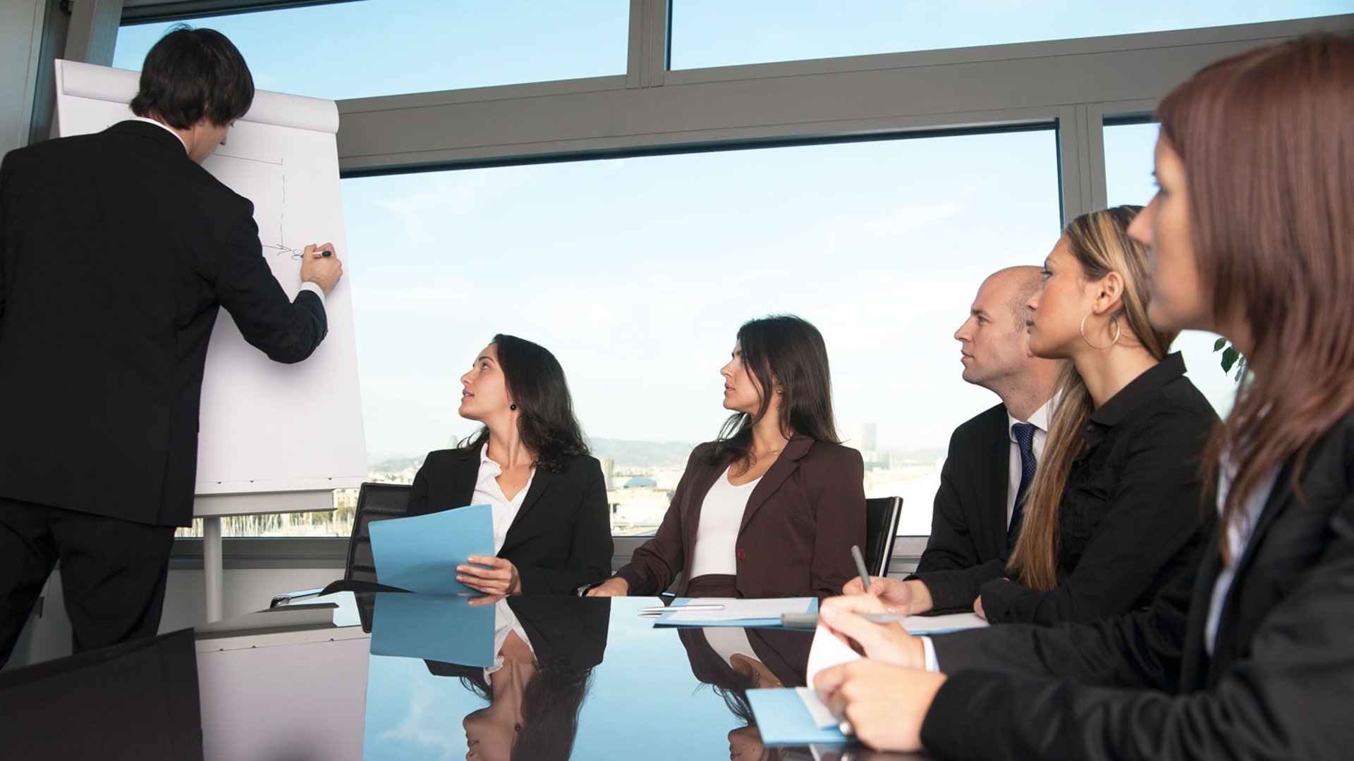 selective focus photography of people sitting on chairs while writing on notebooks