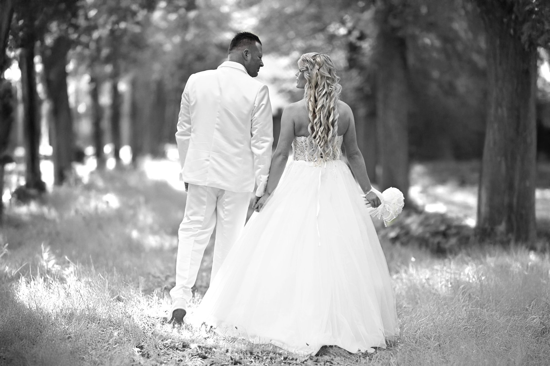 Brautpaar läuft Hand in Hand durch einen Waldweg – Hochzeitsfotograf Möhnesee