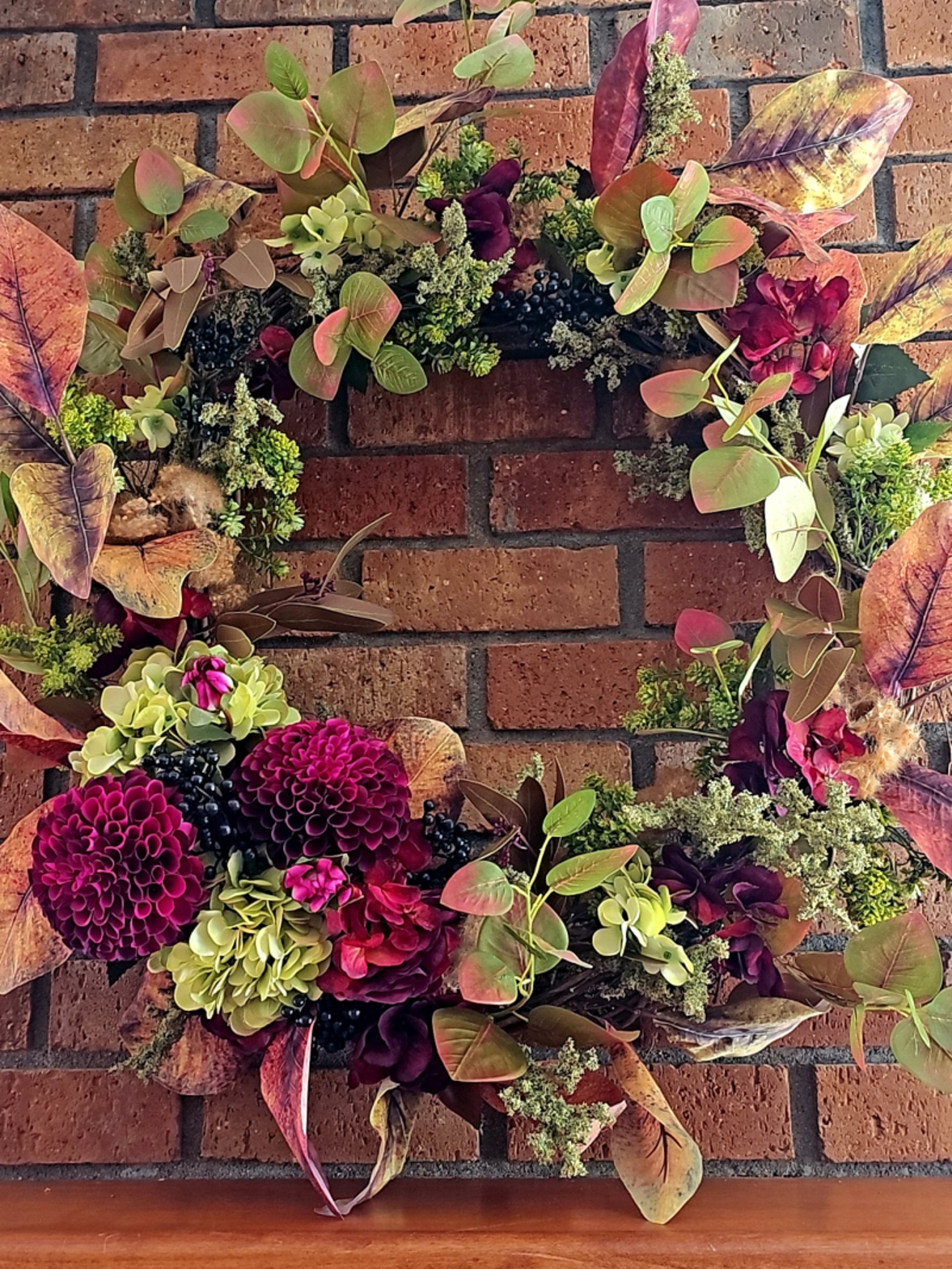 Luxury permanent botanical autumn wreath with terracotta roses, peonies, and fall foliage on a grapevine frame