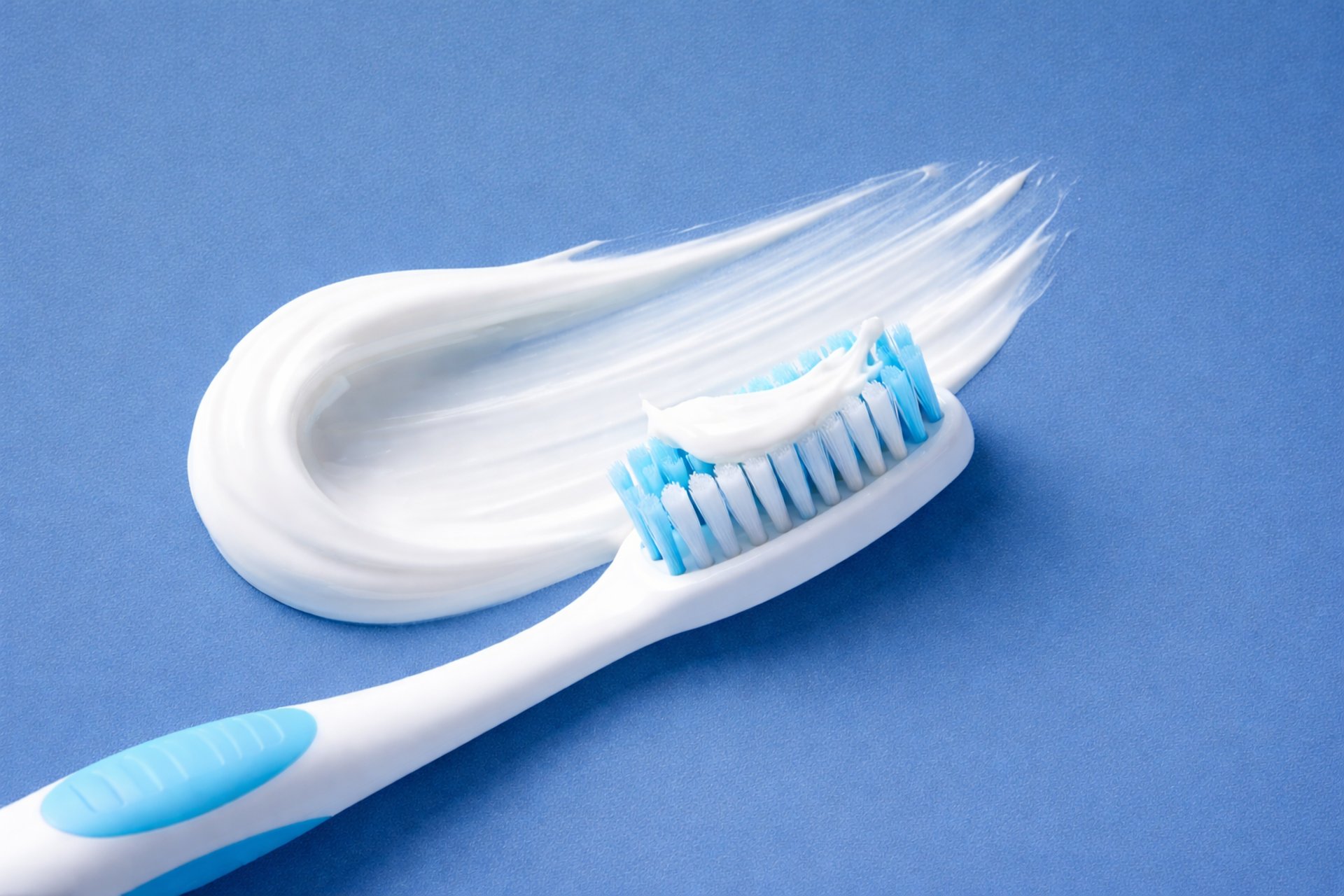 Orange toothbrush with green toothpaste on yellow background