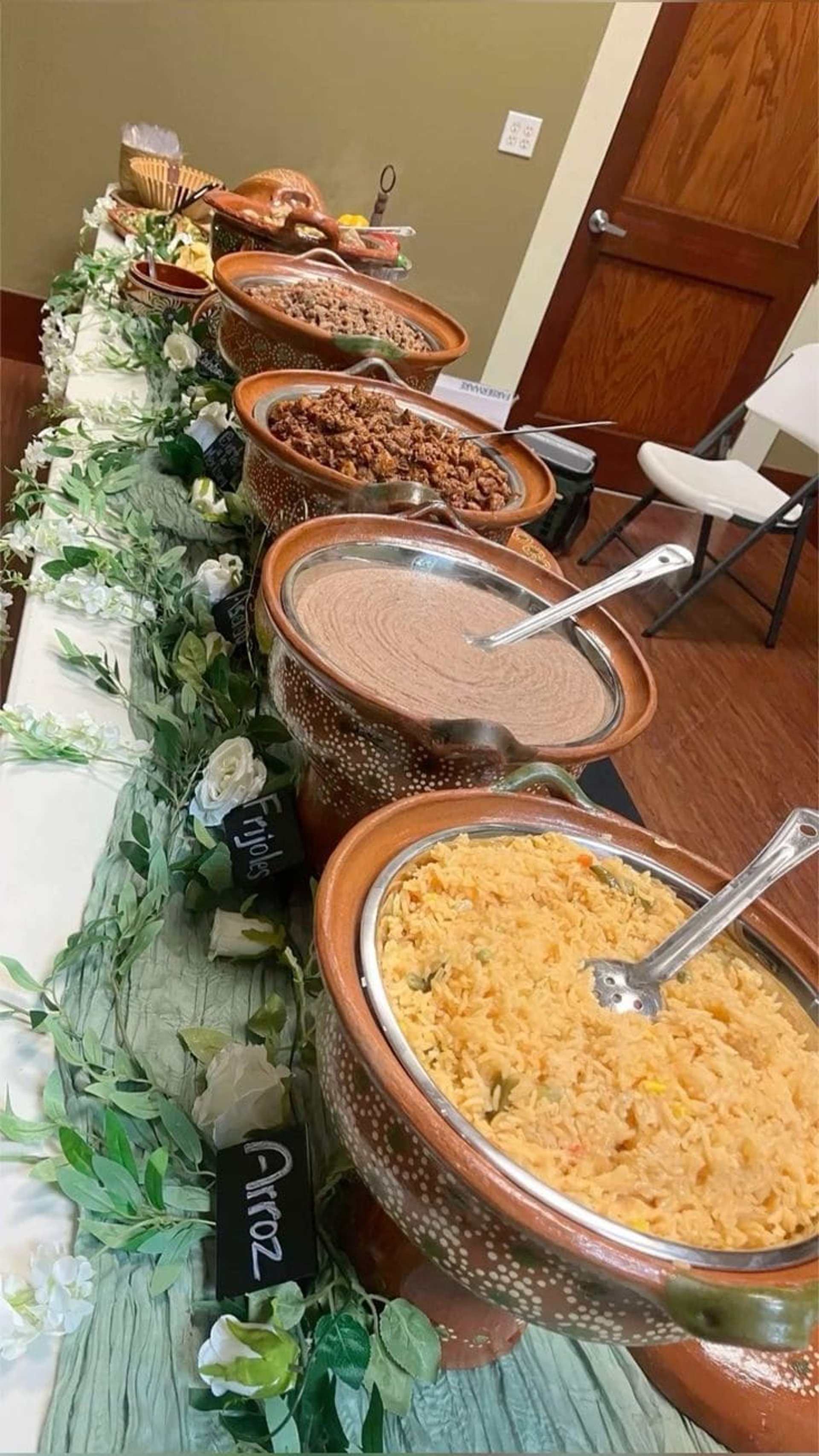 Cazuelas de barro con diferentes tipos de guisos sobre una mesa adornada con hojas y flores